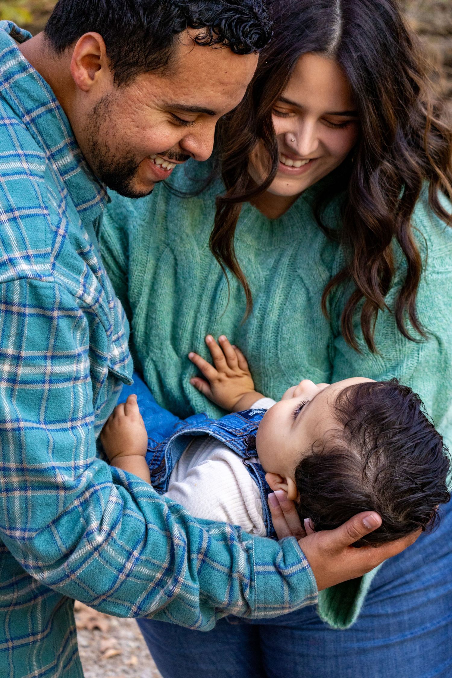 A mom and dad holding their baby and smiling at him