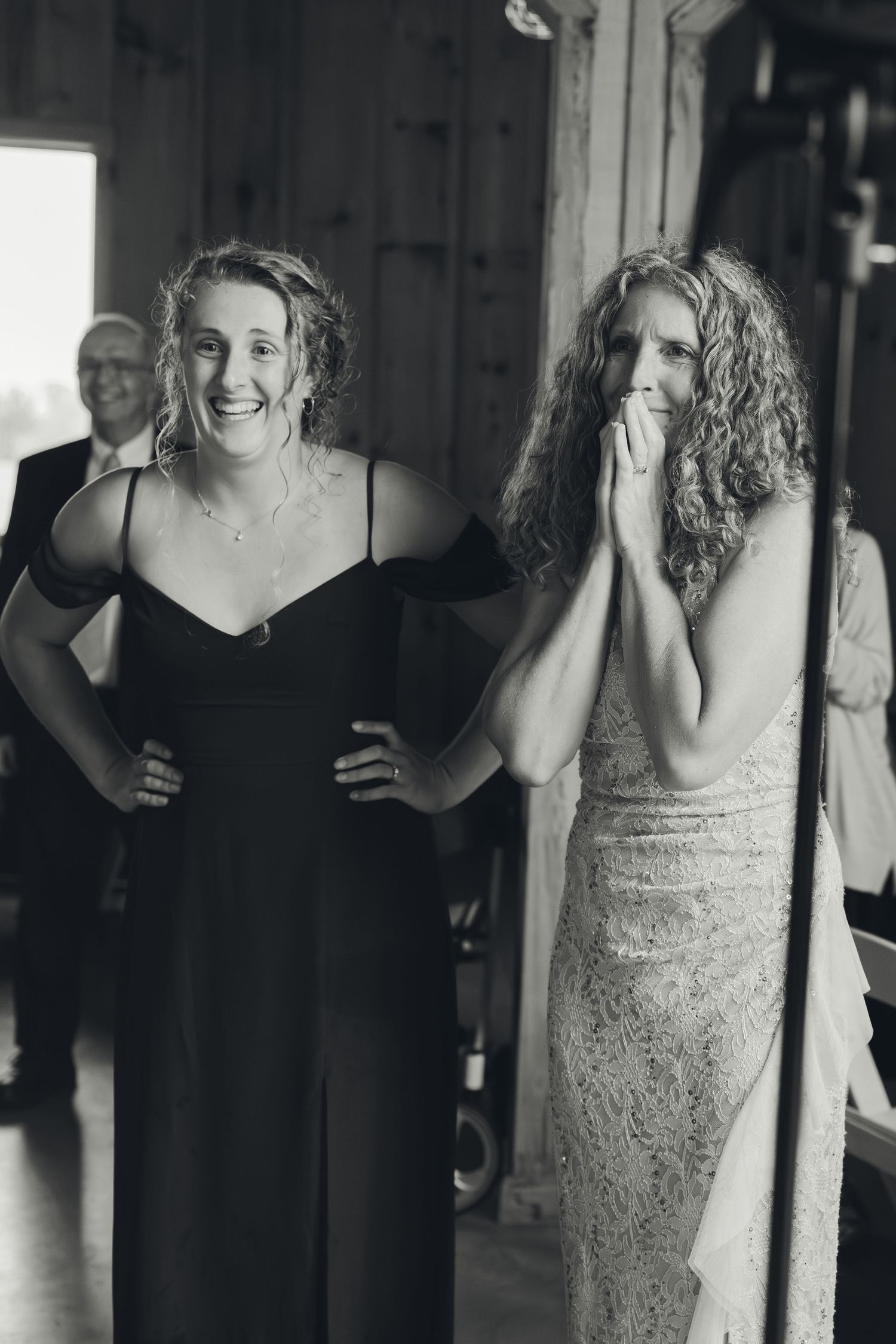 Two women laugh and cry with emotion in black and white photo during a heartfelt wedding moment.