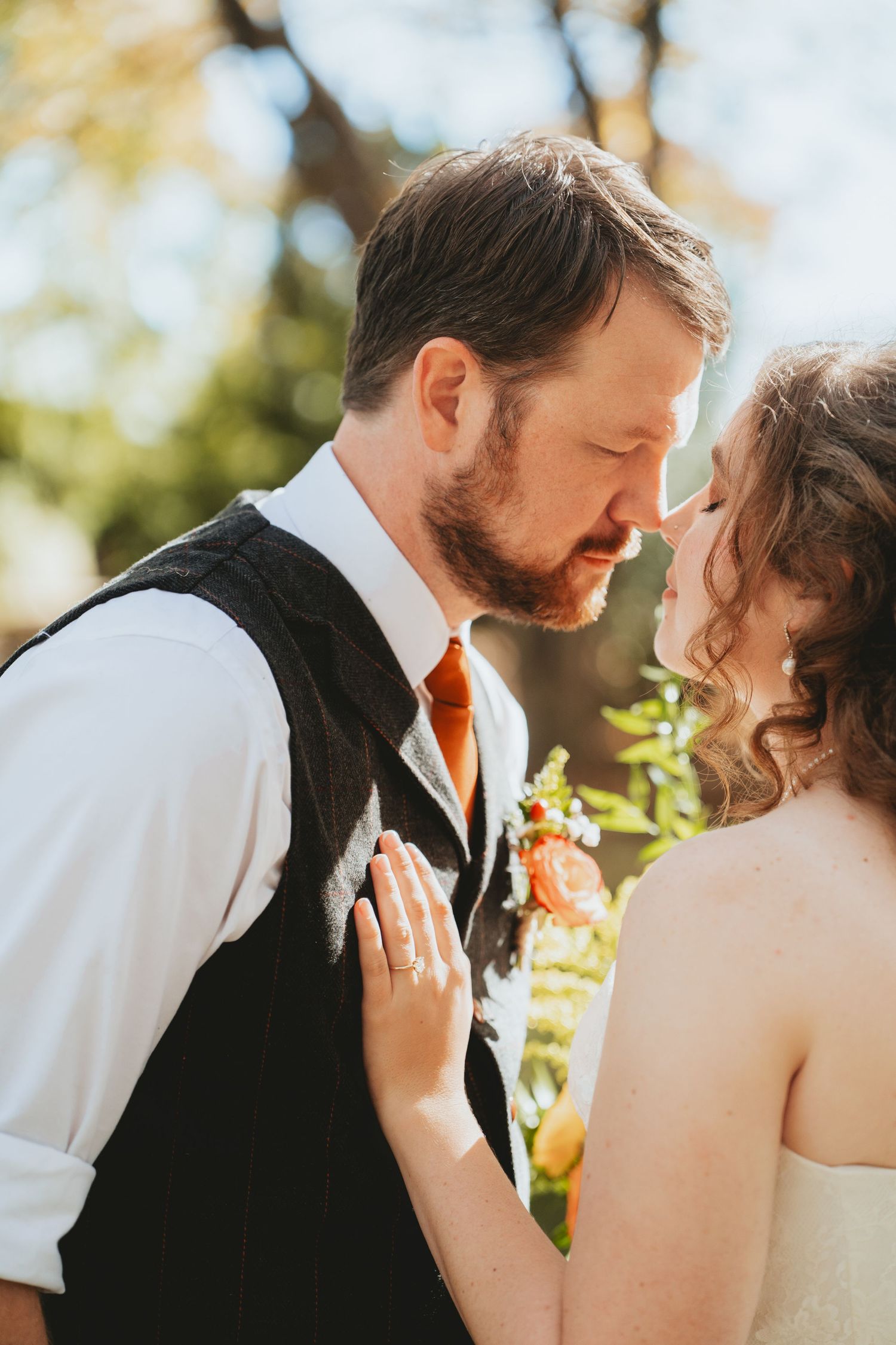 Bride and groom share an intimate moment, nearly kissing, at their outdoor fall wedding ceremony.