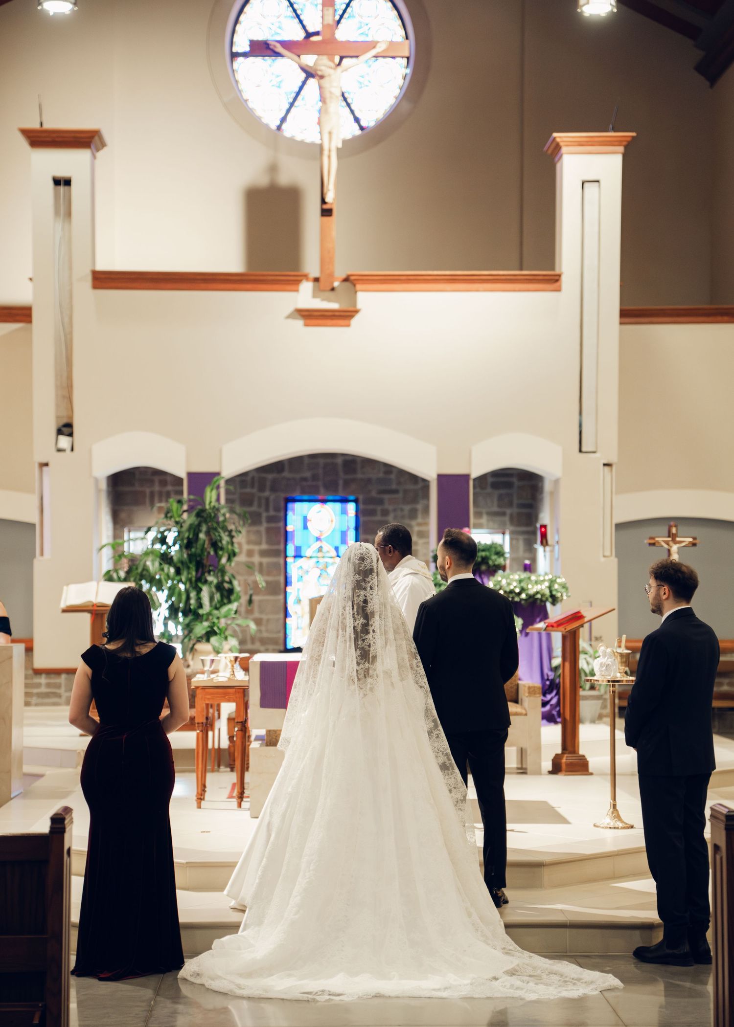 Bride and groom stand at church altar beneath large crucifix during wedding ceremony.