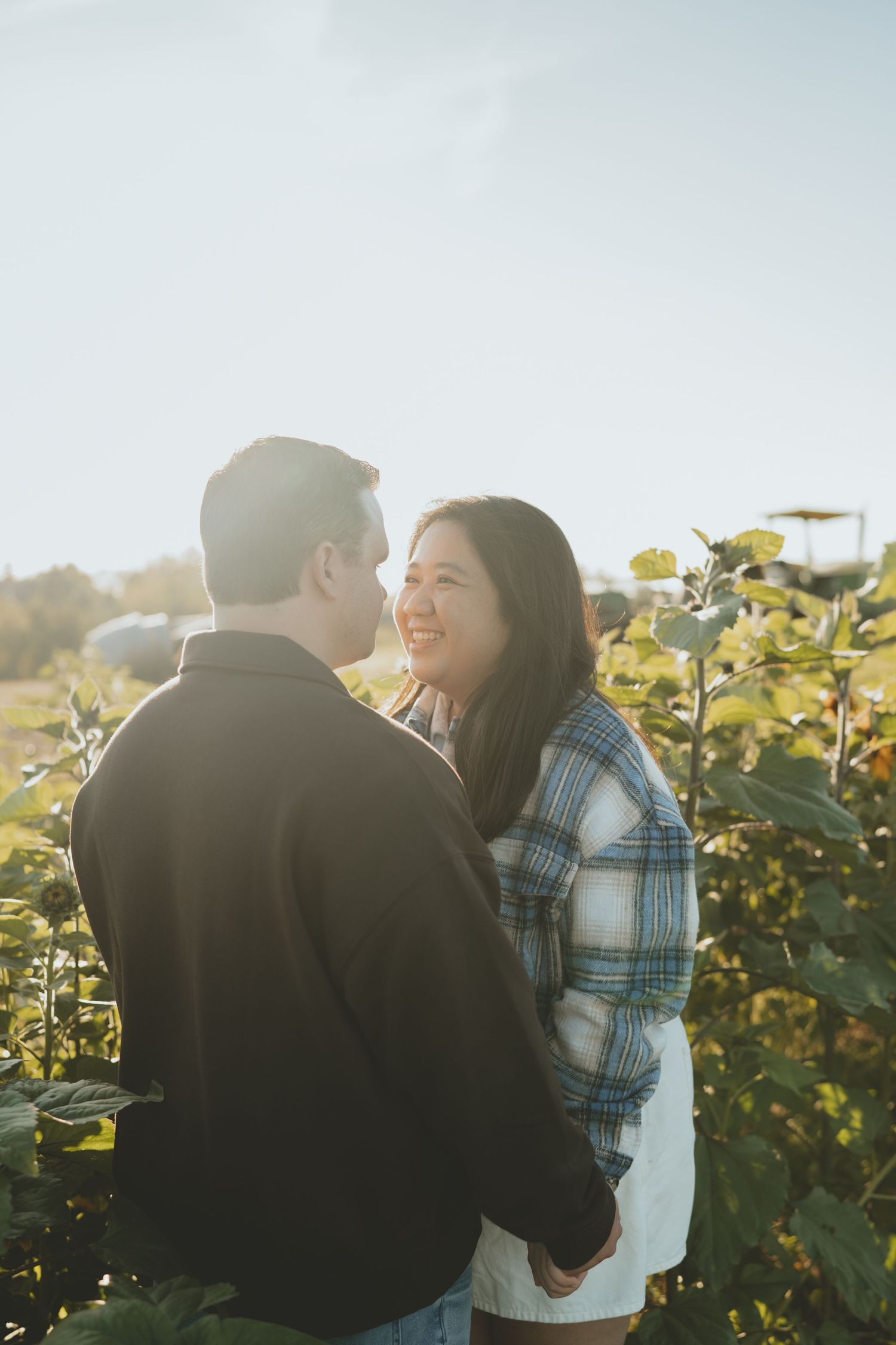 Couple sharing a tender moment in a sunlit garden, woman smiling warmly.