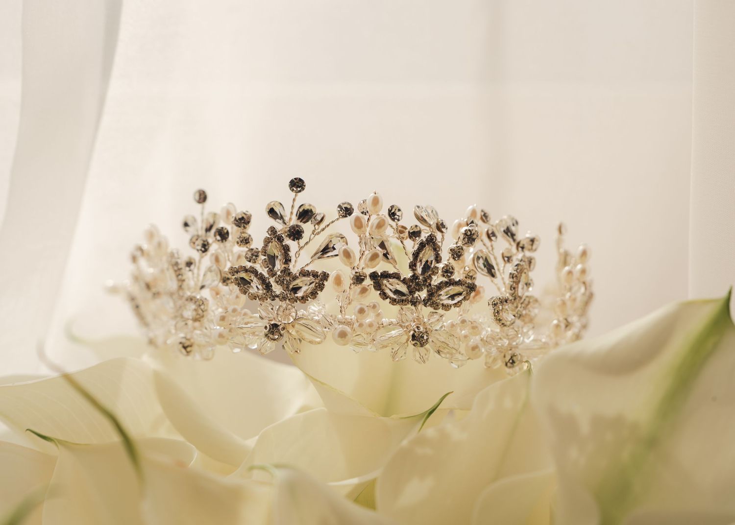Ornate silver and black crystal bridal tiara resting on white roses.