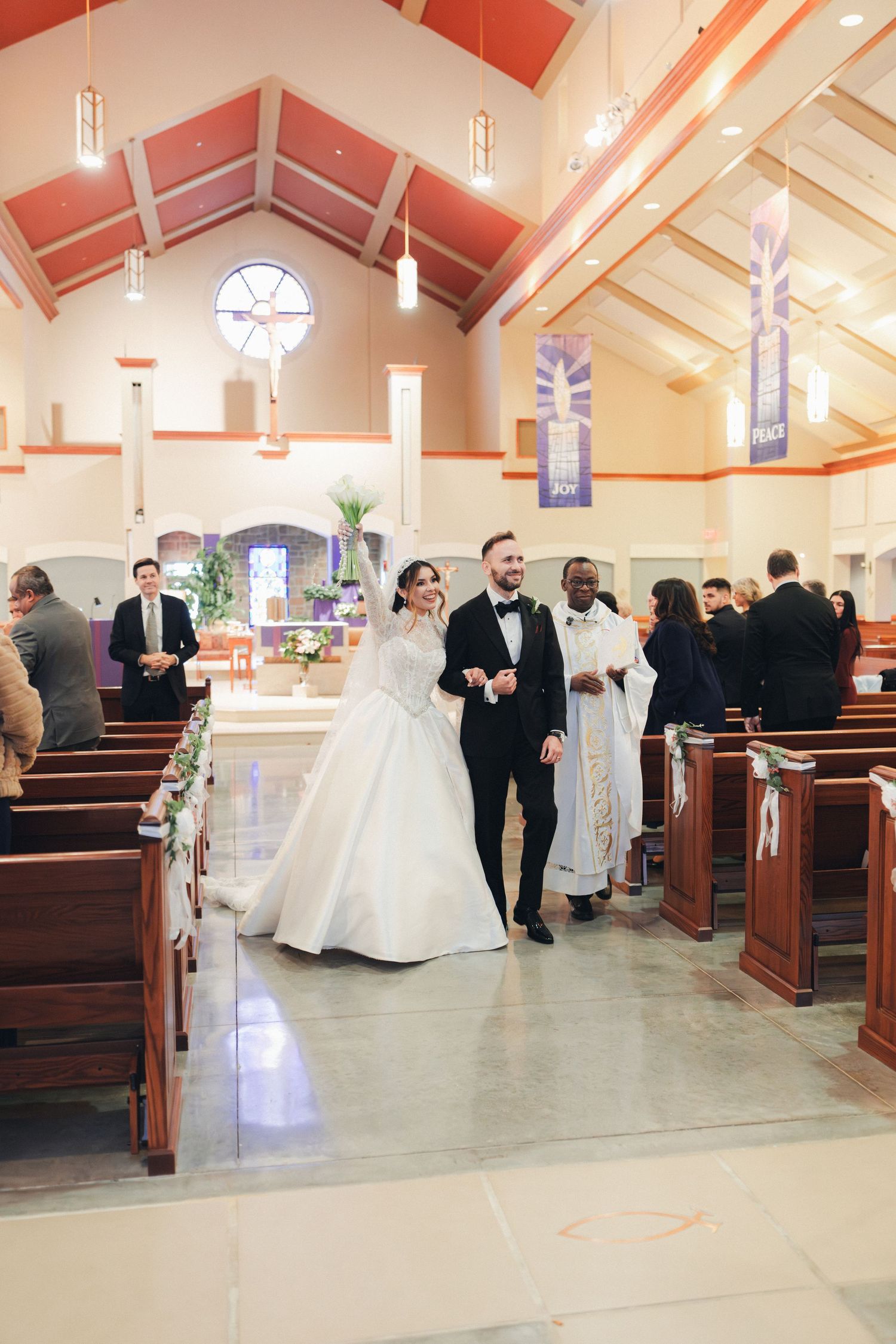 Newlyweds walk down church aisle together after wedding ceremony with guests celebrating.