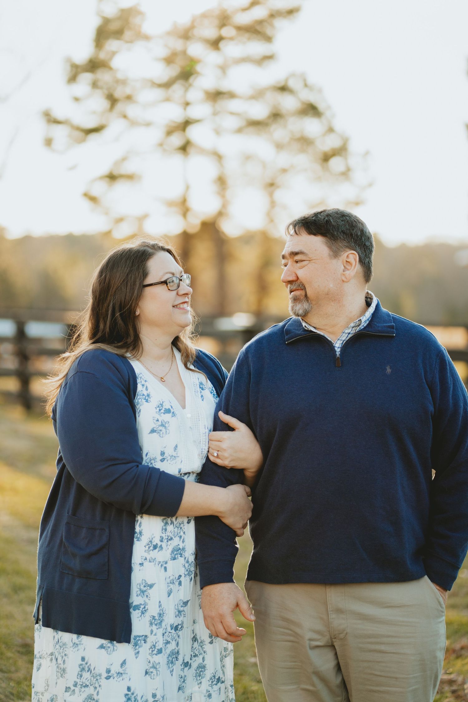 Smiling couple walking arm in arm in a sunny outdoor setting.
