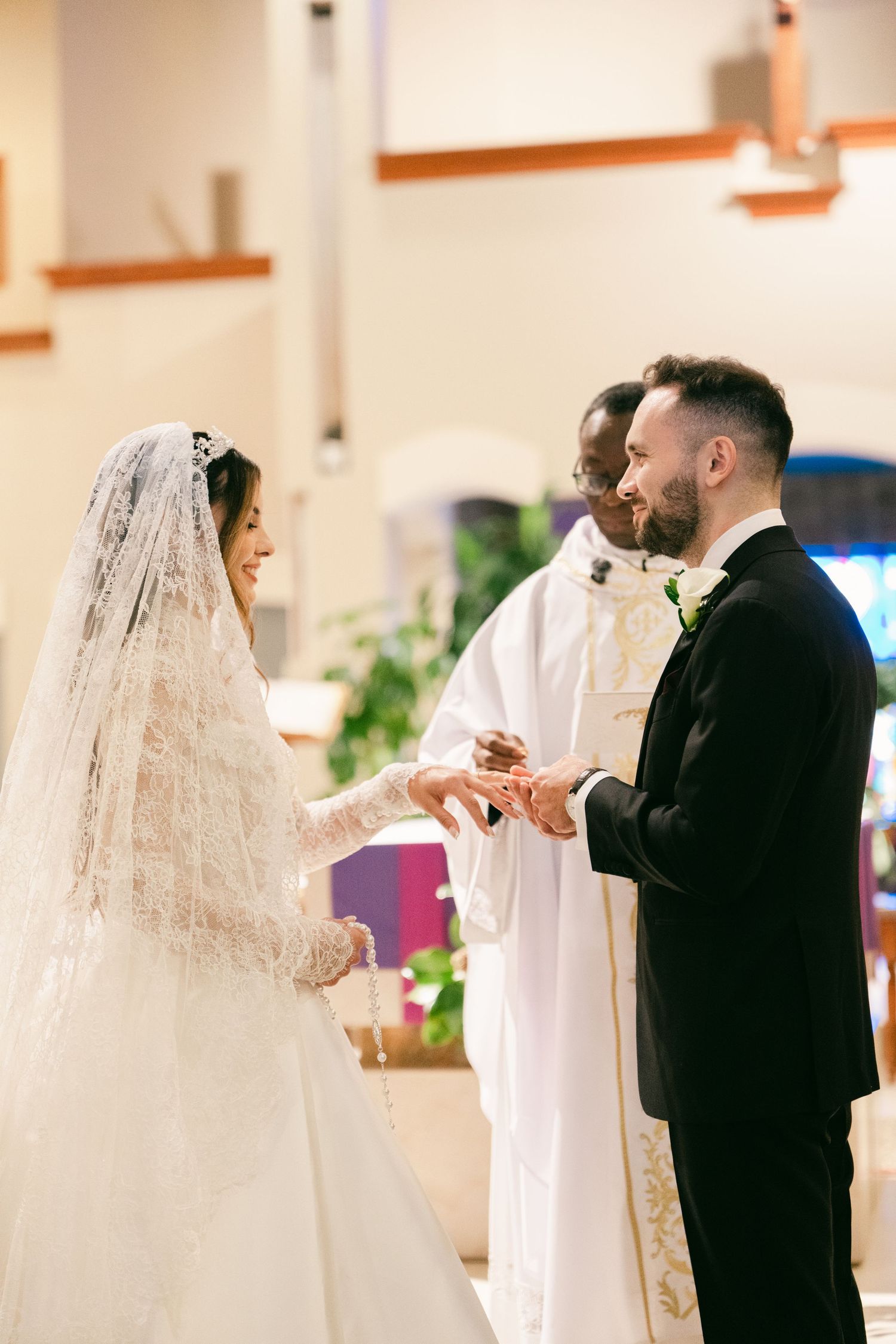 Bride and groom exchanging rings at church altar with officiant.