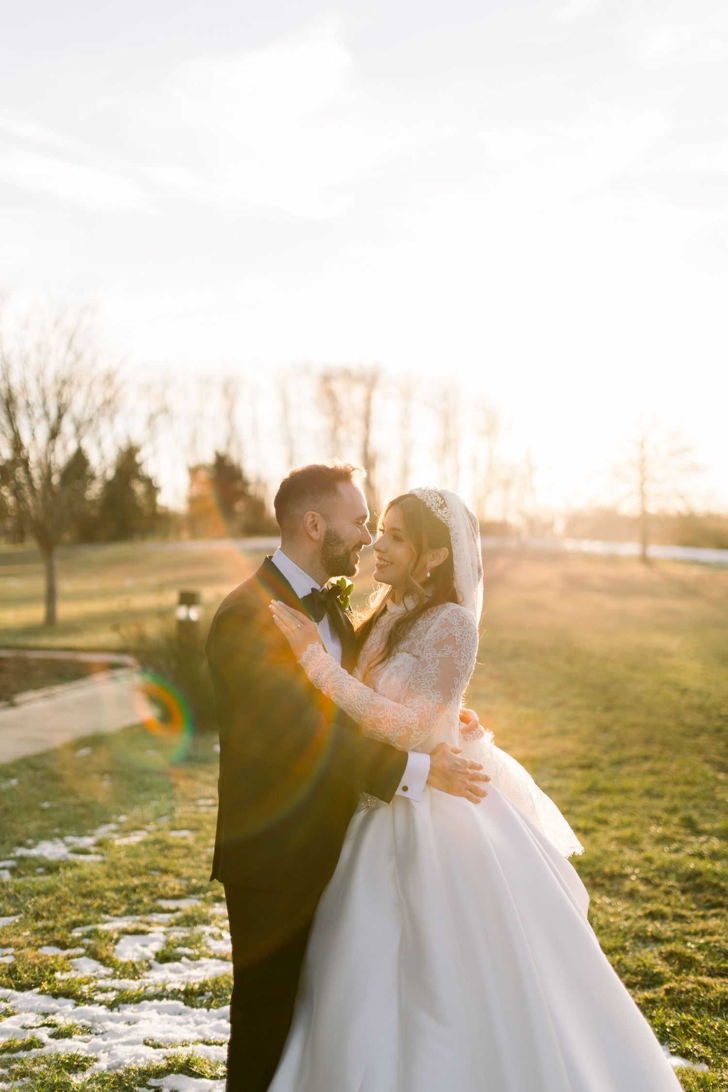 Bride and groom nearly kissing in golden sunset light during romantic outdoor wedding portrait.