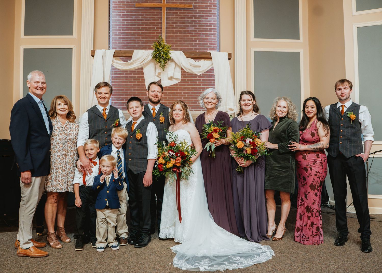 Large family group portrait with bride and groom at a fall-themed church wedding ceremony.