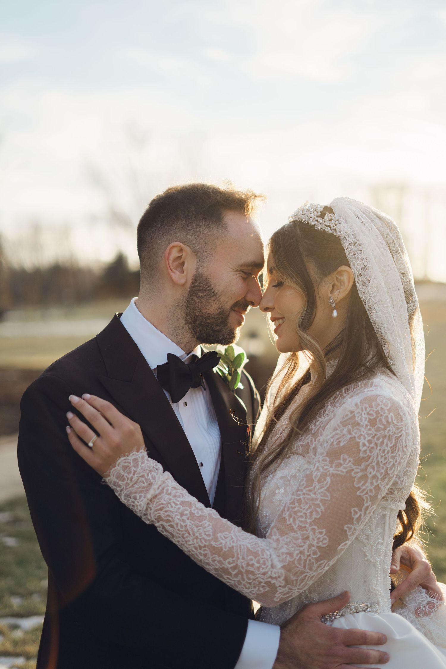 Bride and groom share an intimate forehead touch moment outdoors during golden hour wedding photography.