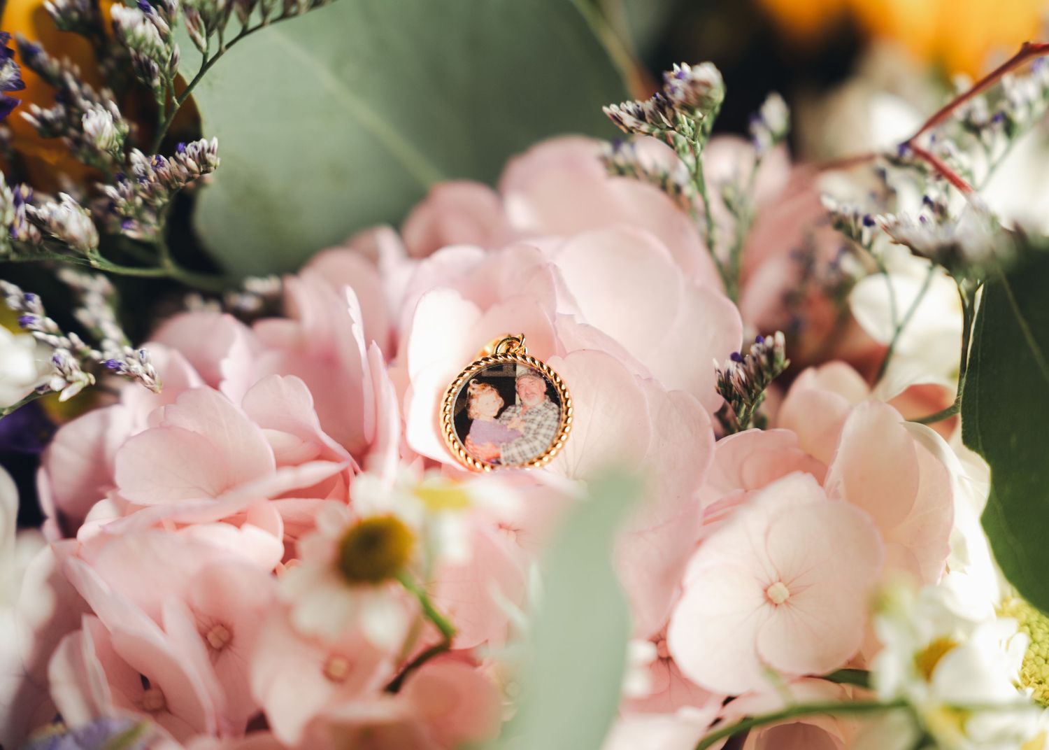 A delicate gold oval locket with a portrait nestled among soft pink hydrangeas and lavender wildflowers.
