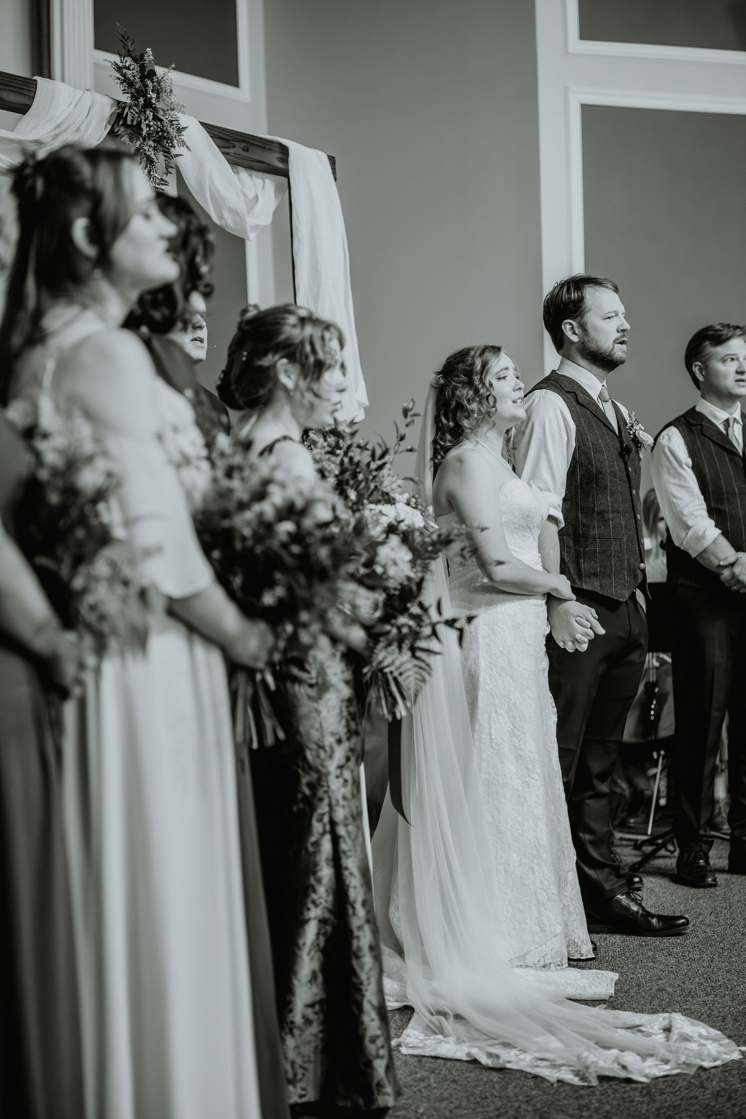 Black and white photo of wedding party standing at the altar during the ceremony.
