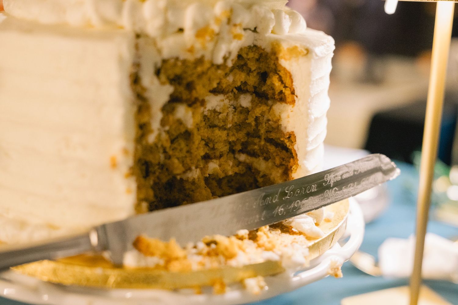 Close-up of layered carrot wedding cake being cut with silver knife revealing moist interior layers.