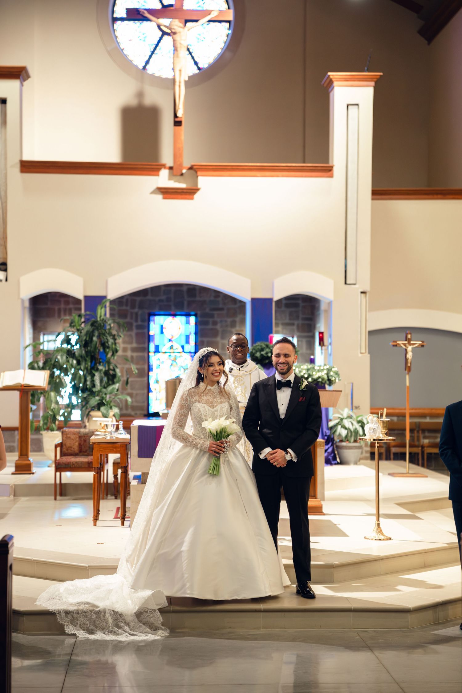 Bride and groom stand at church altar with officiant after exchanging vows during wedding.
