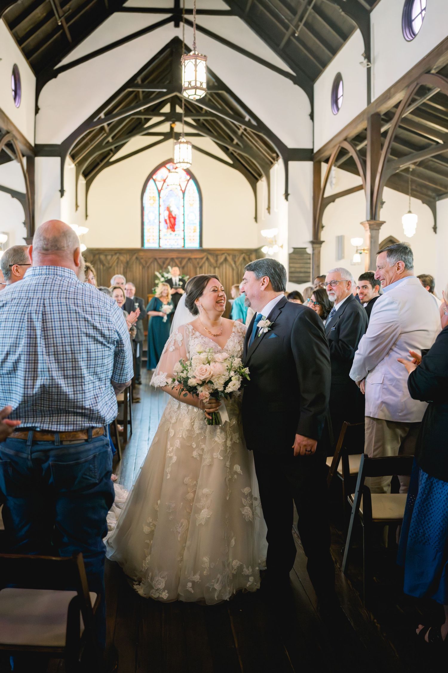 Newlyweds walk joyfully down church aisle together after ceremony as guests stand and celebrate.