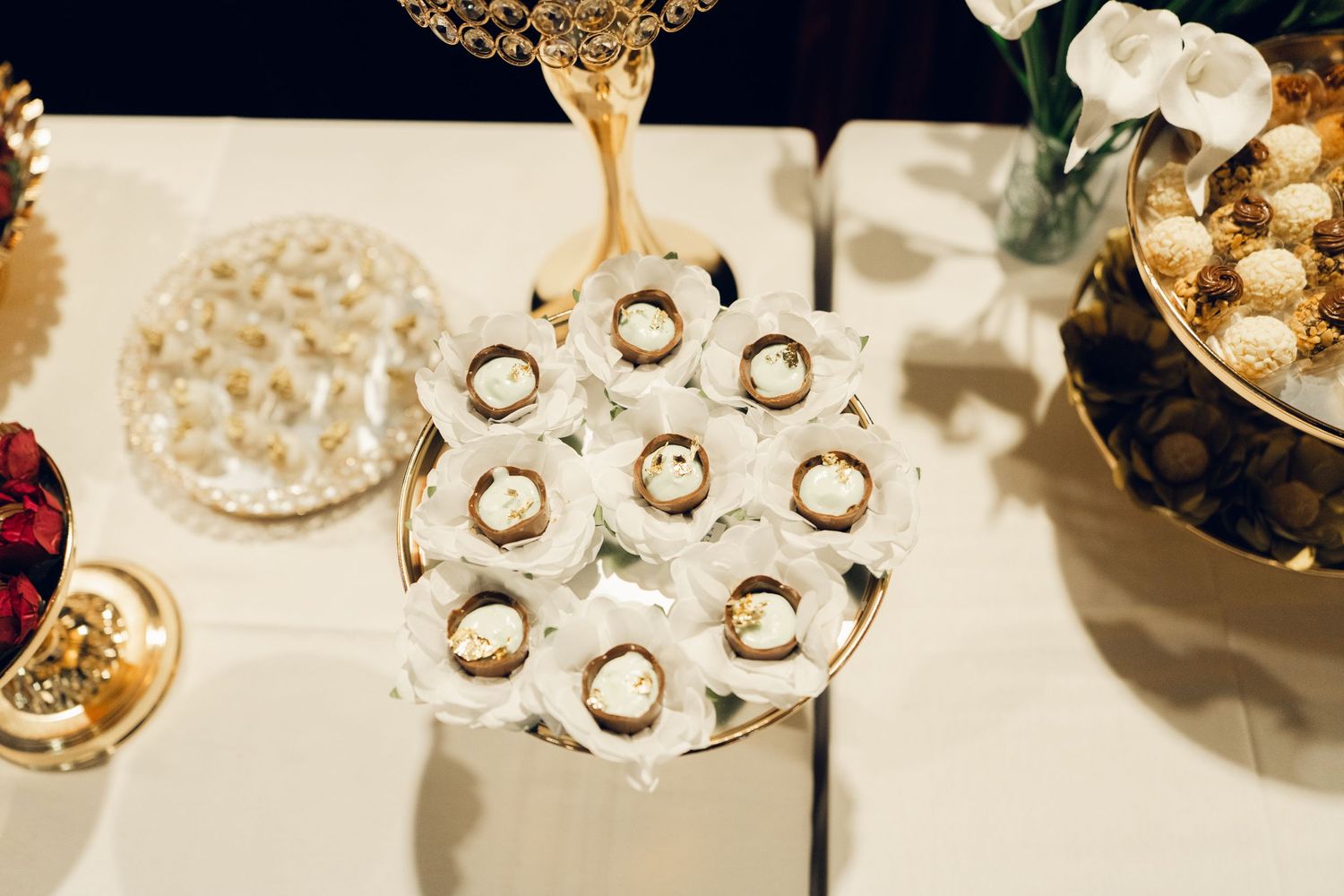 Elegant wedding dessert table featuring Ferrero Rocher chocolates arranged on a decorative gold tiered stand.