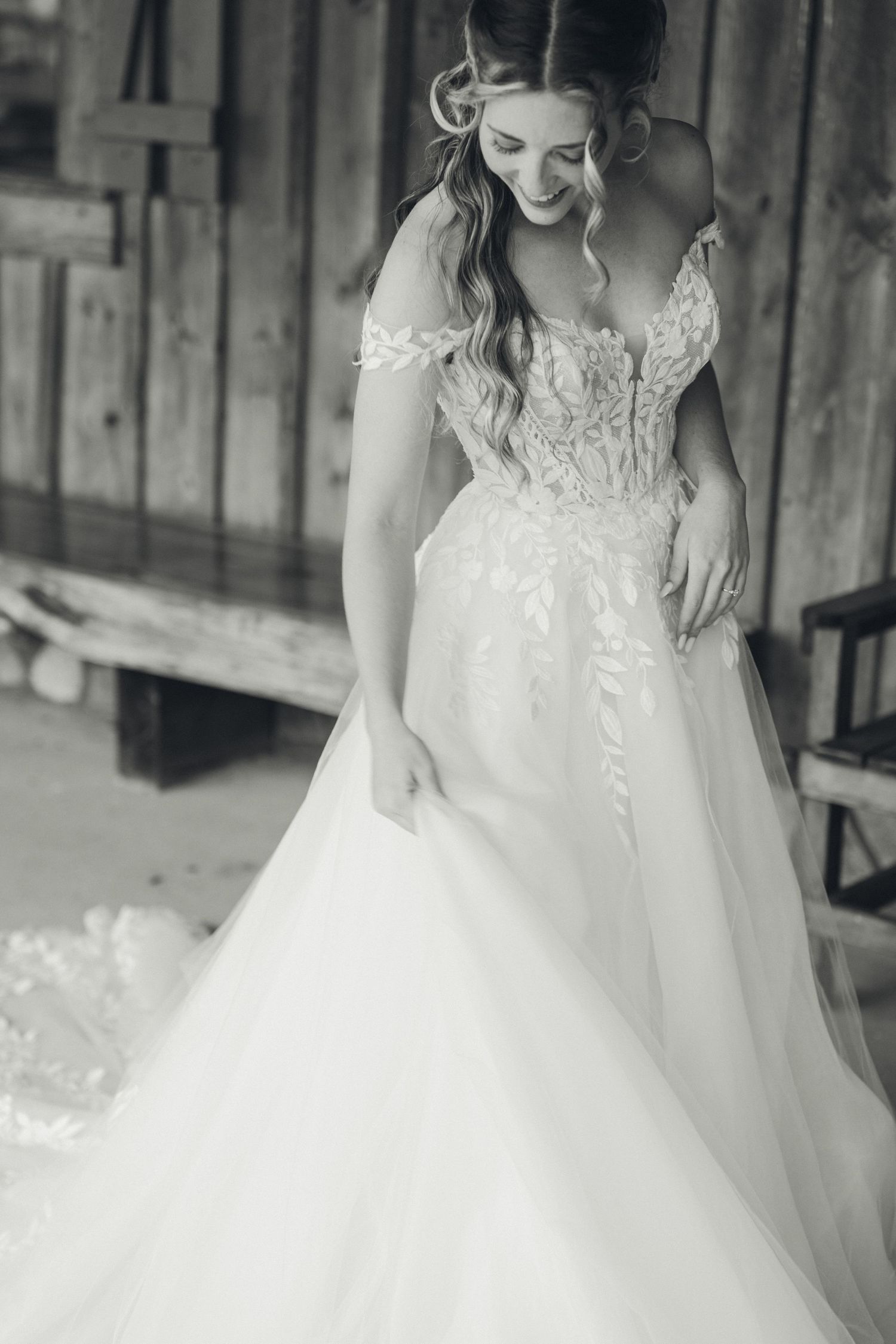Bride in elegant off-shoulder lace ball gown wedding dress, black and white photo.