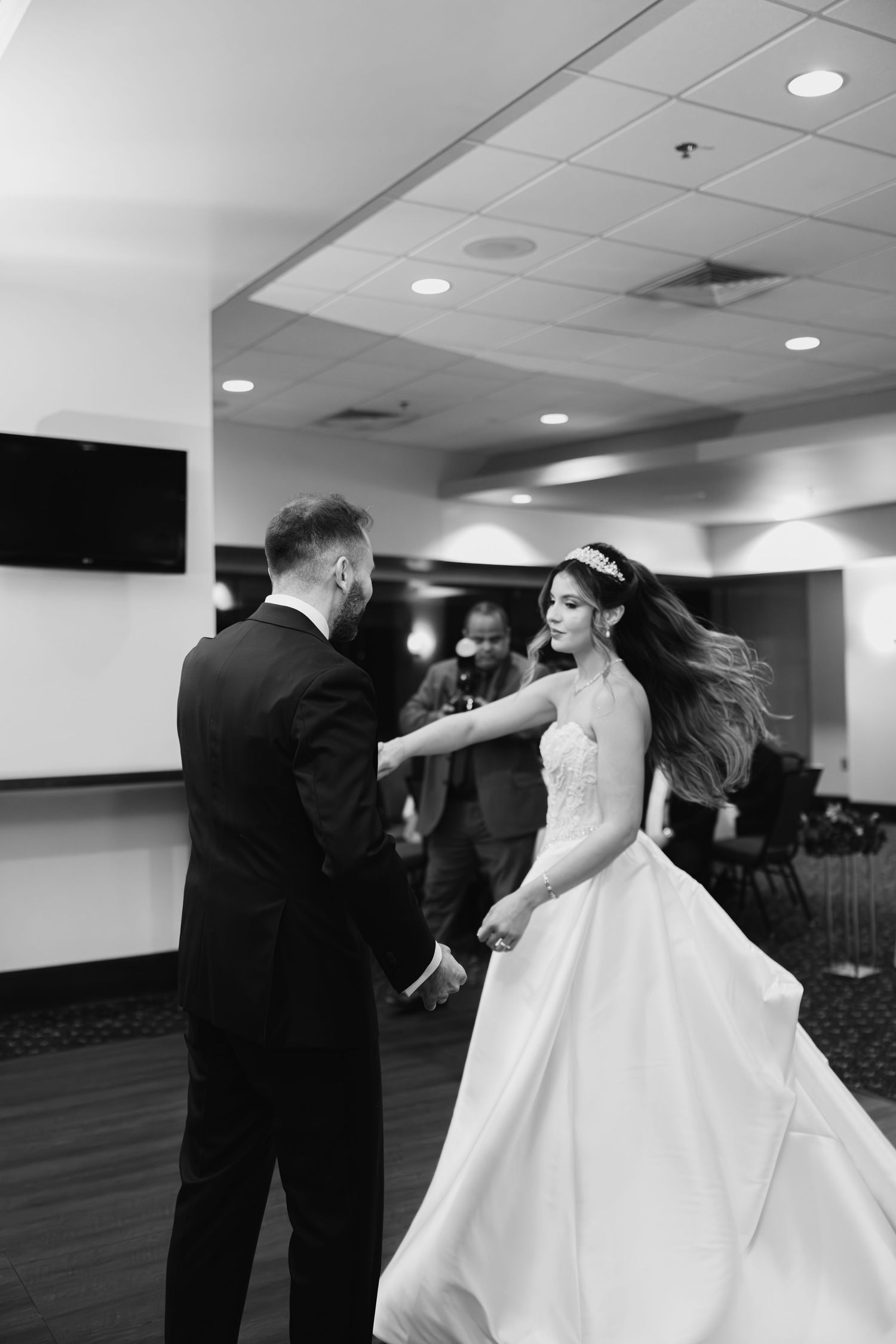 Black and white photo of bride and groom sharing first dance, brides hair flowing gracefully.