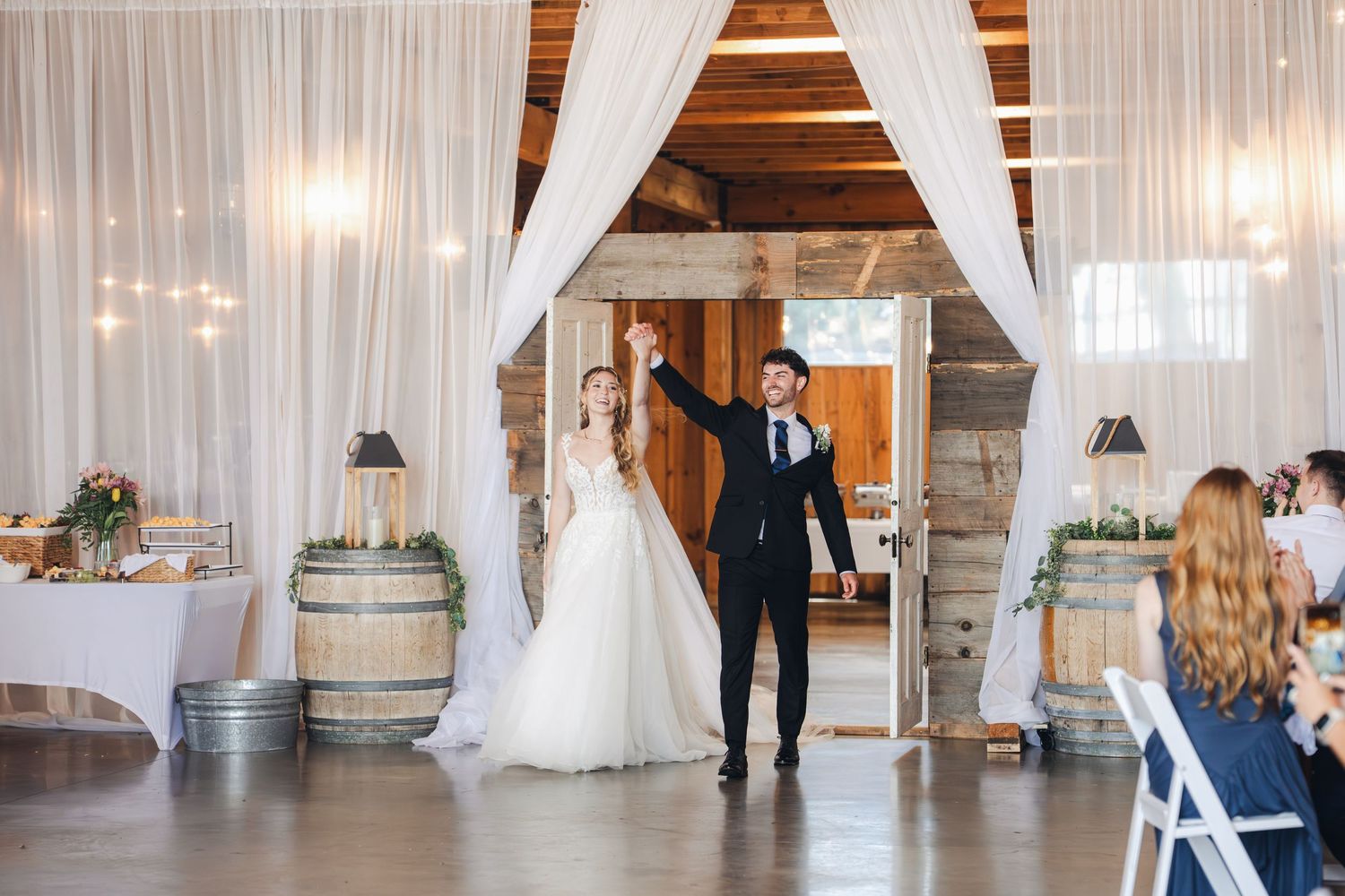 Bride and groom making grand entrance at rustic barn wedding reception venue.
