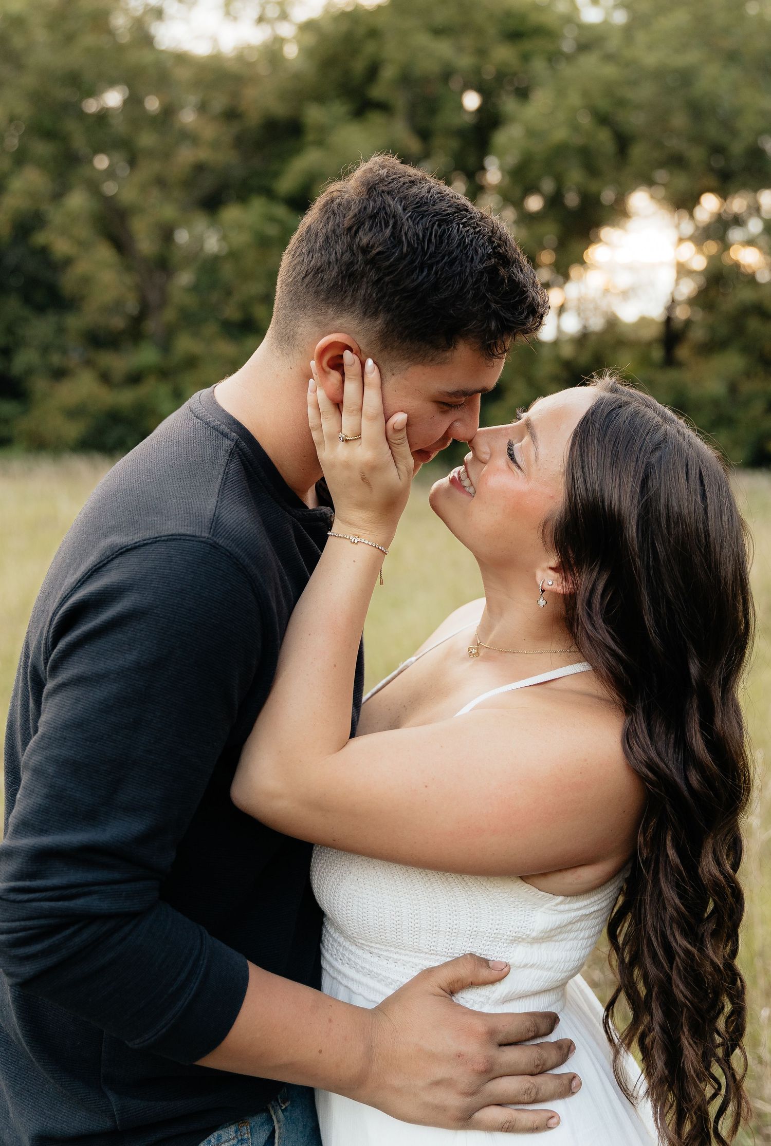 A romantic newlywed couple sharing tender kisses during their wedding photoshoot in a sunlit outdoor setting.