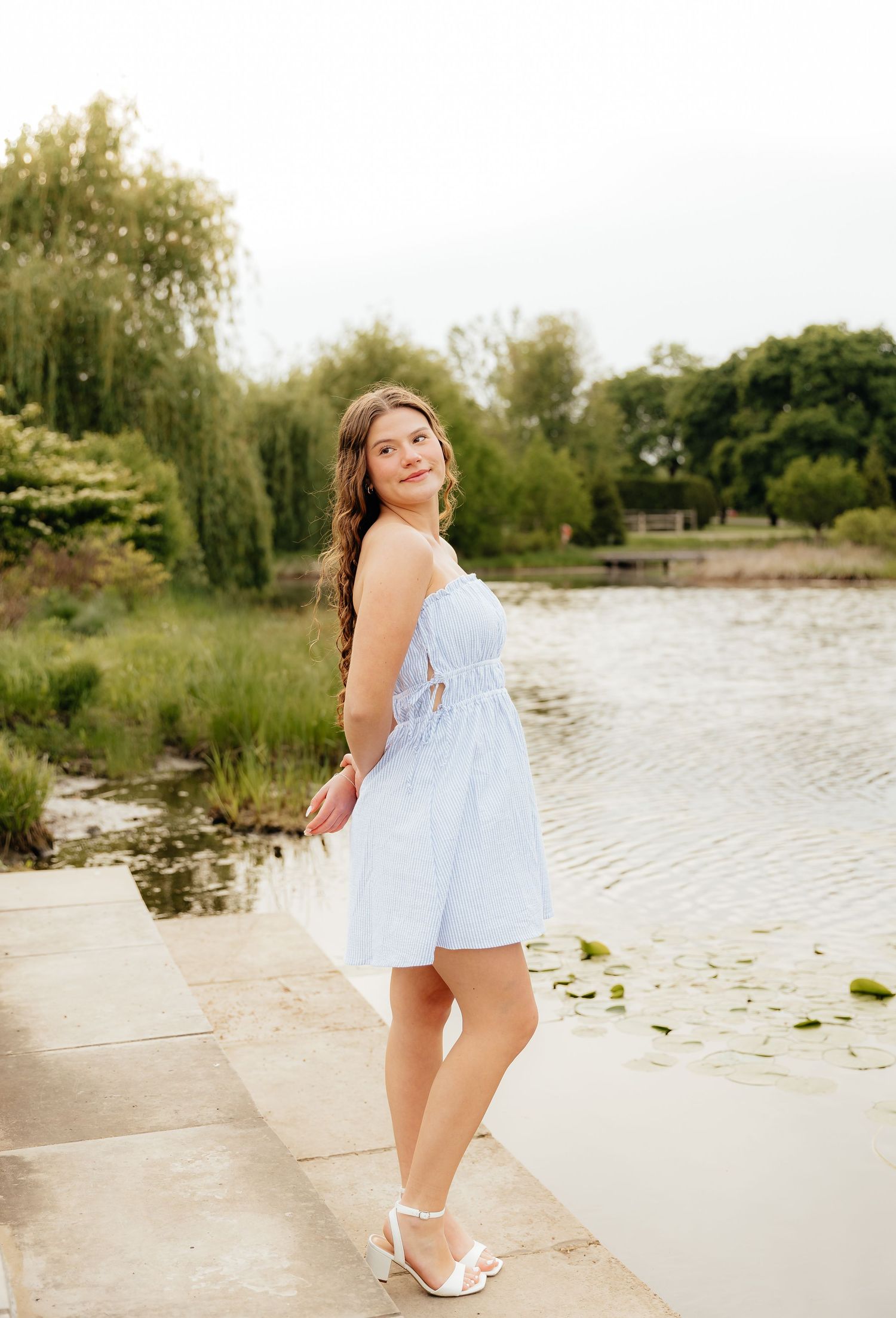 A summer portrait session by a tranquil pond wearing a light blue outfit.