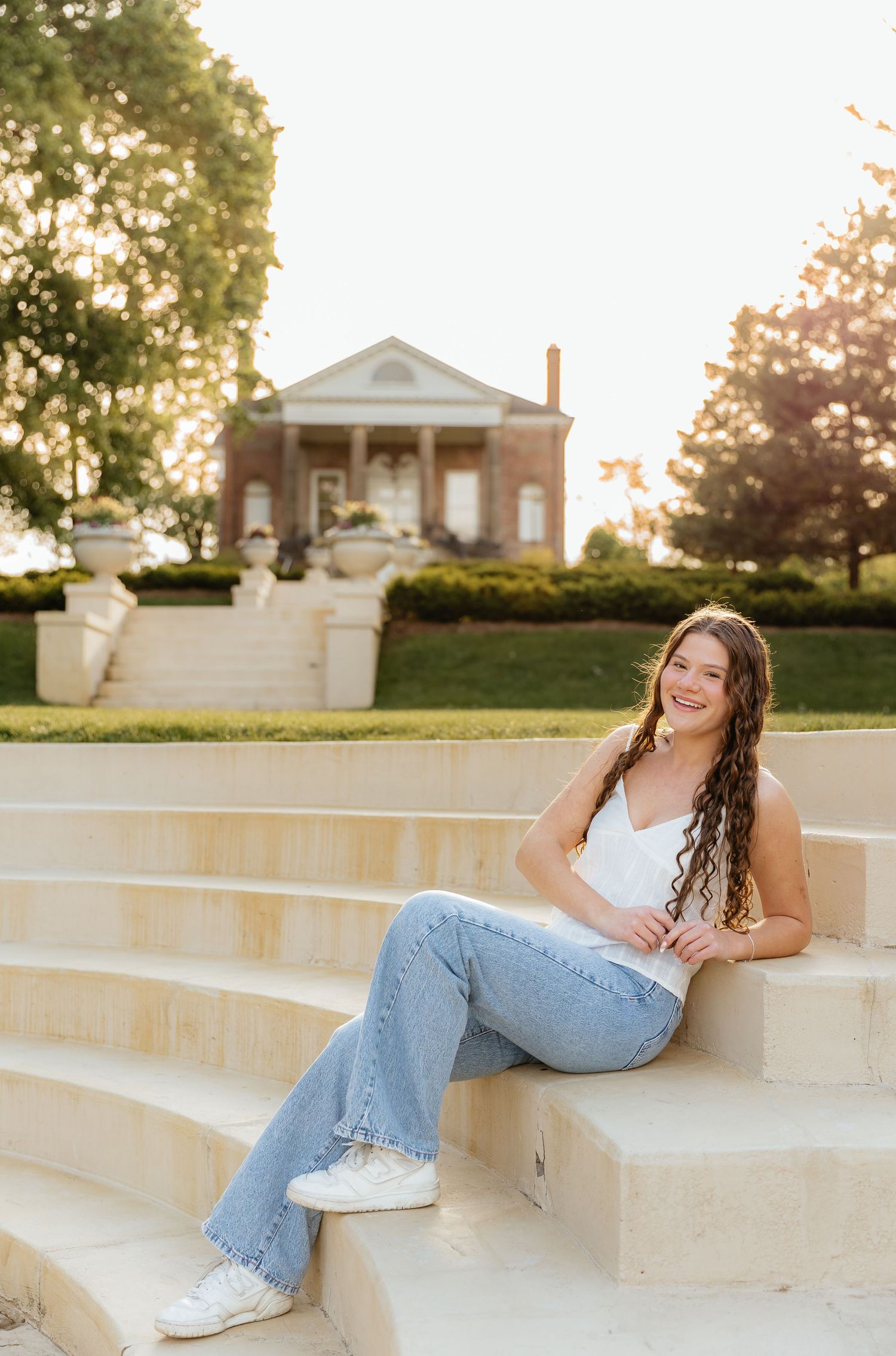 A relaxed portrait session on concrete steps in front of a stately brick building during golden hour.