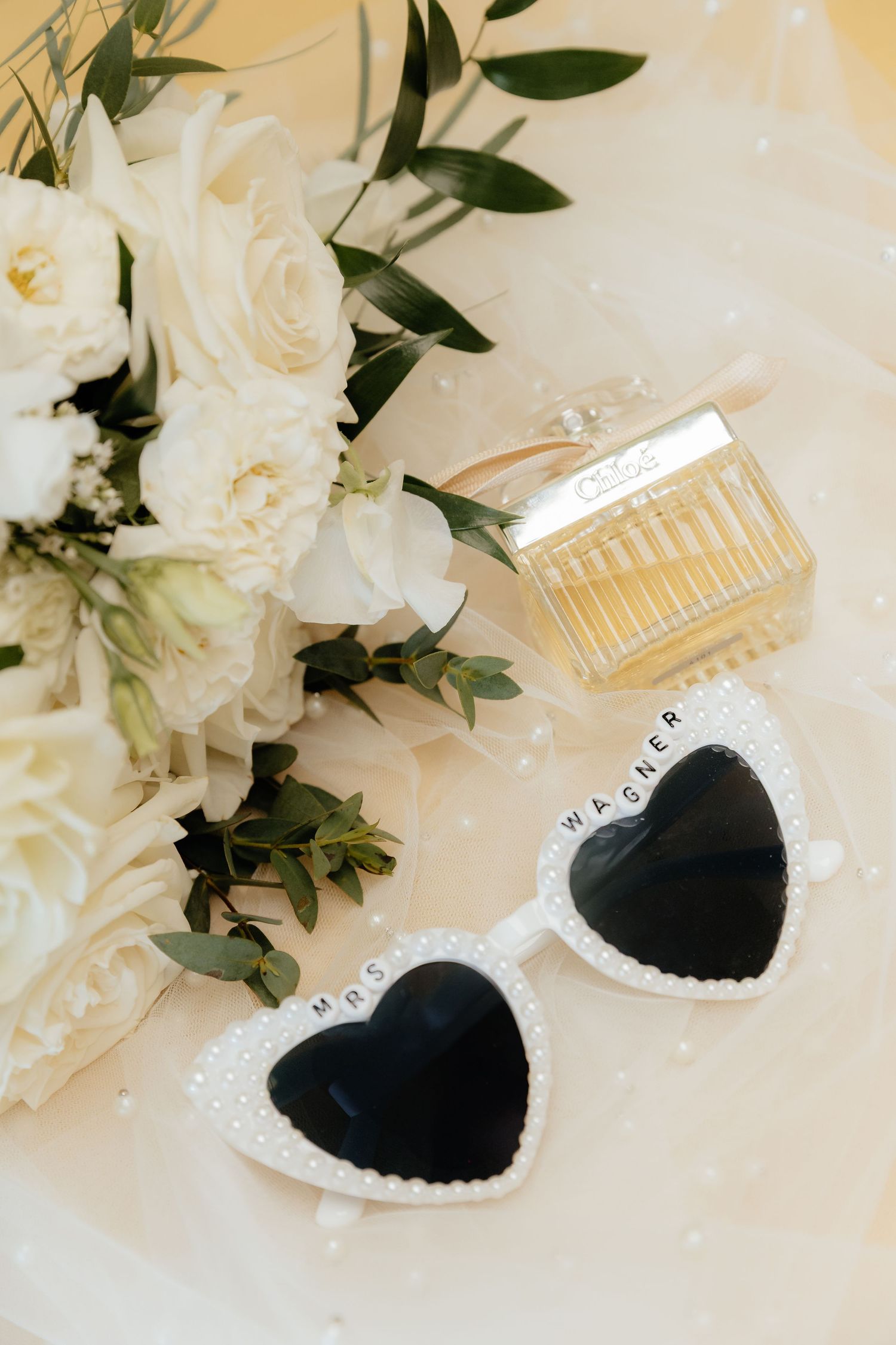 White floral arrangement with decorative heart shaped locket and delicate hair combs against a light background.