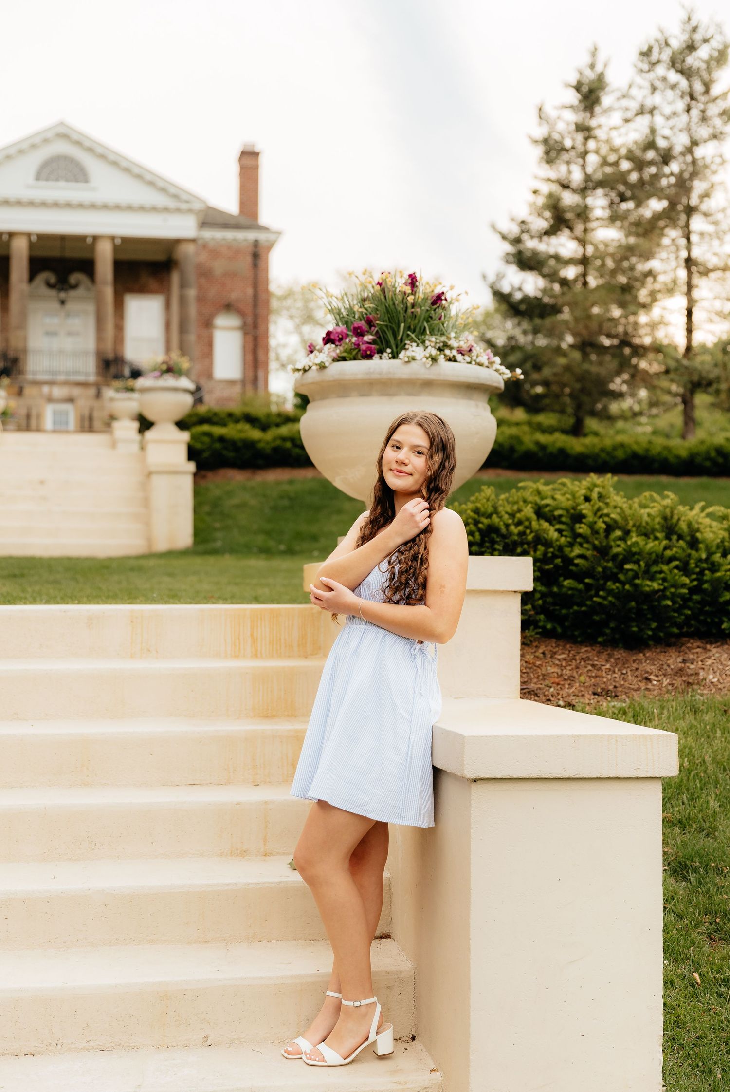 A stylish summer photoshoot with a decorative planter and classic architecture in the background.