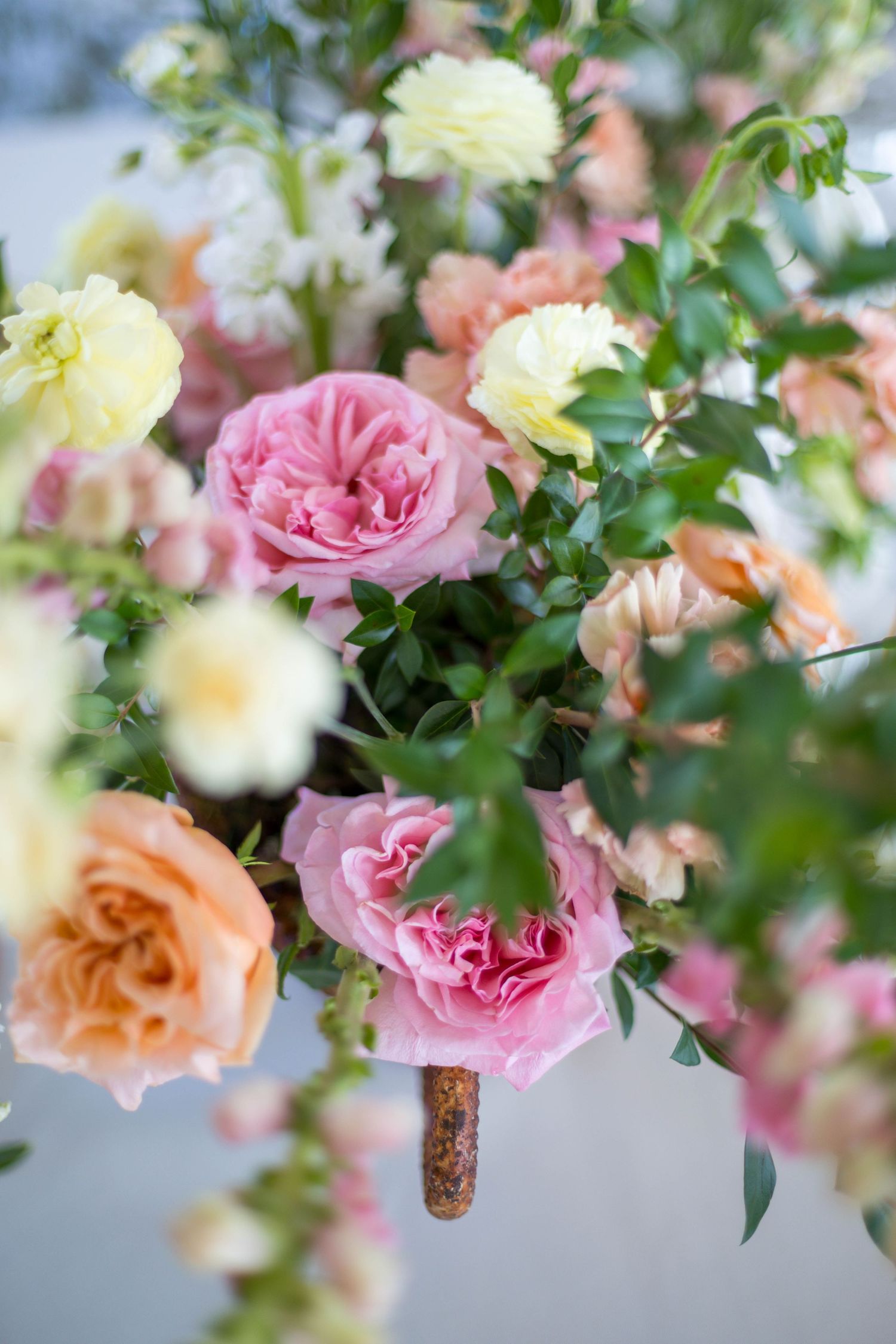Lush floral arrangement featuring pink roses, peach blooms, and yellow flowers with green foliage.