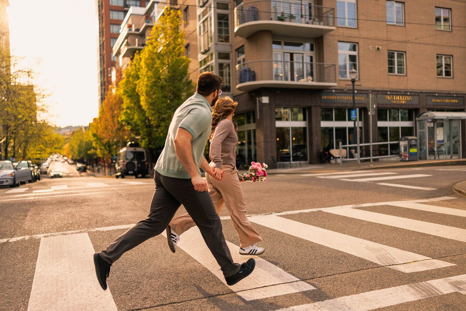 Person leaping across sunny urban crosswalk with long shadow creating dramatic silhouette at sunset.