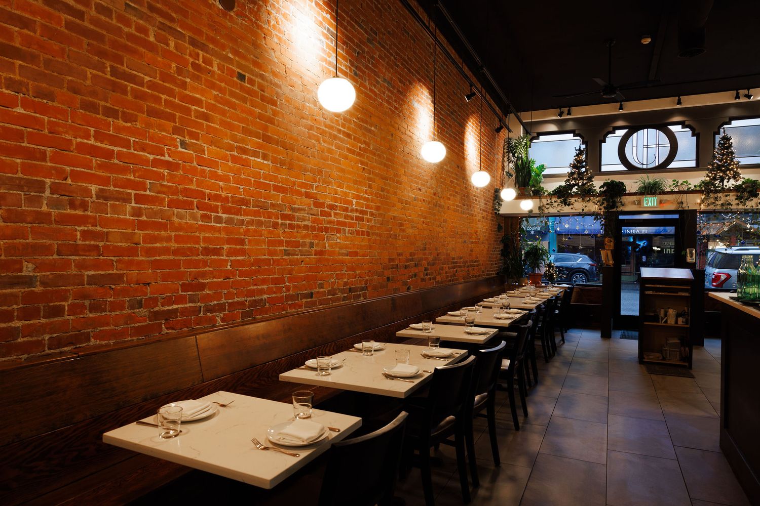 Modern restaurant interior with exposed brick walls, pendant lighting, and white tablecloths creates an intimate dining ambiance.