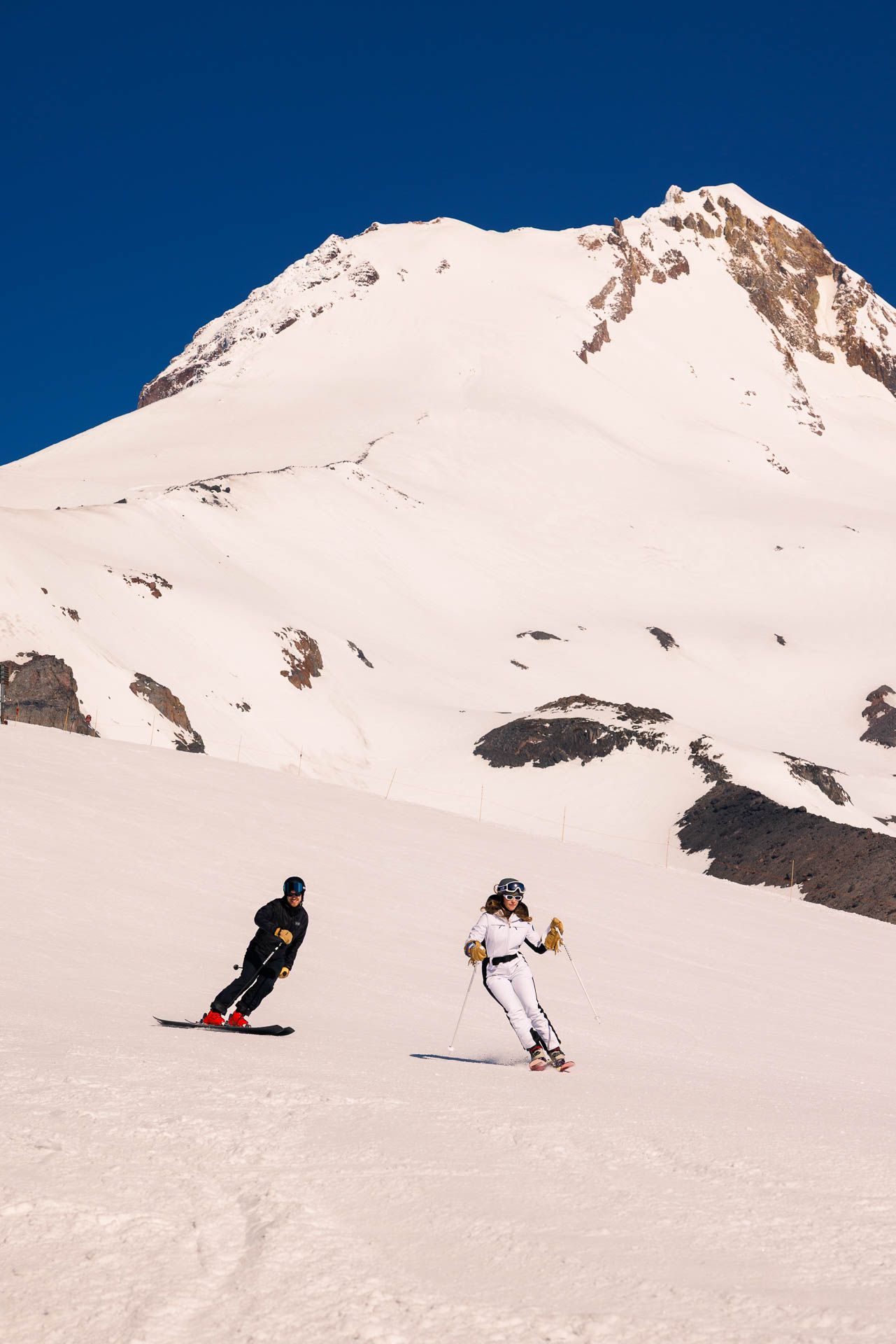 A series of snowy mountain slopes shown in panoramic view with skiers carving fresh tracks in deep powder snow.
