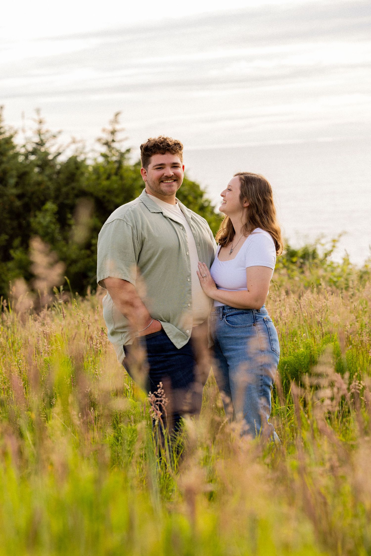 A couple shares a joyful moment together in a wildflower meadow during golden hour.