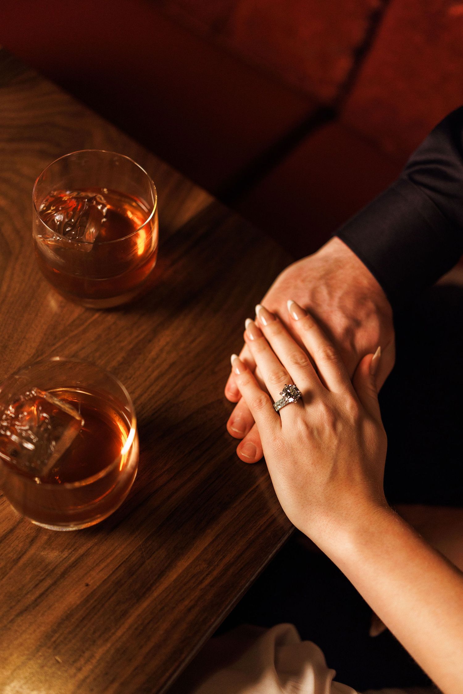 A couple holding hands at the bar while enjoying a cocktail