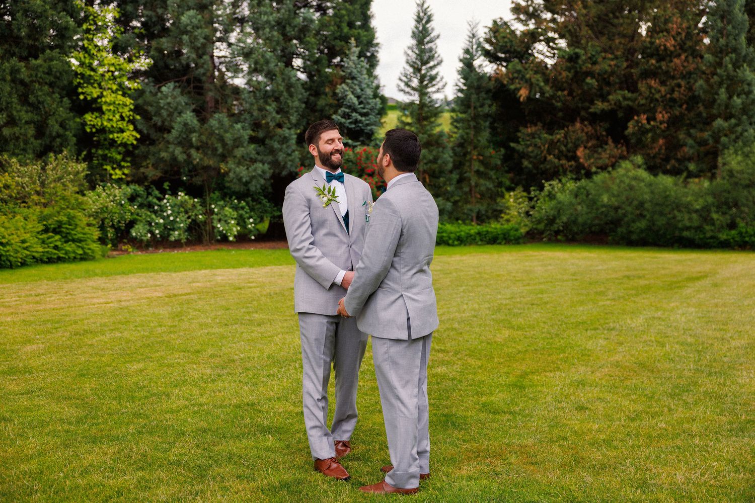 Couple sharing an intimate moment in a garden with evergreen trees.