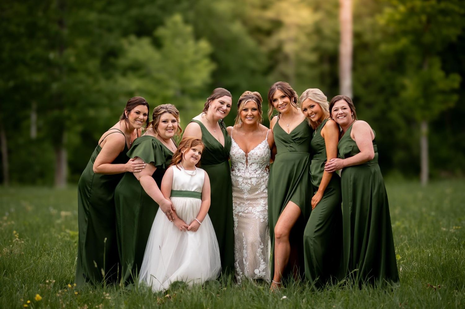 Wedding party in forest setting wearing emerald green and white dresses.