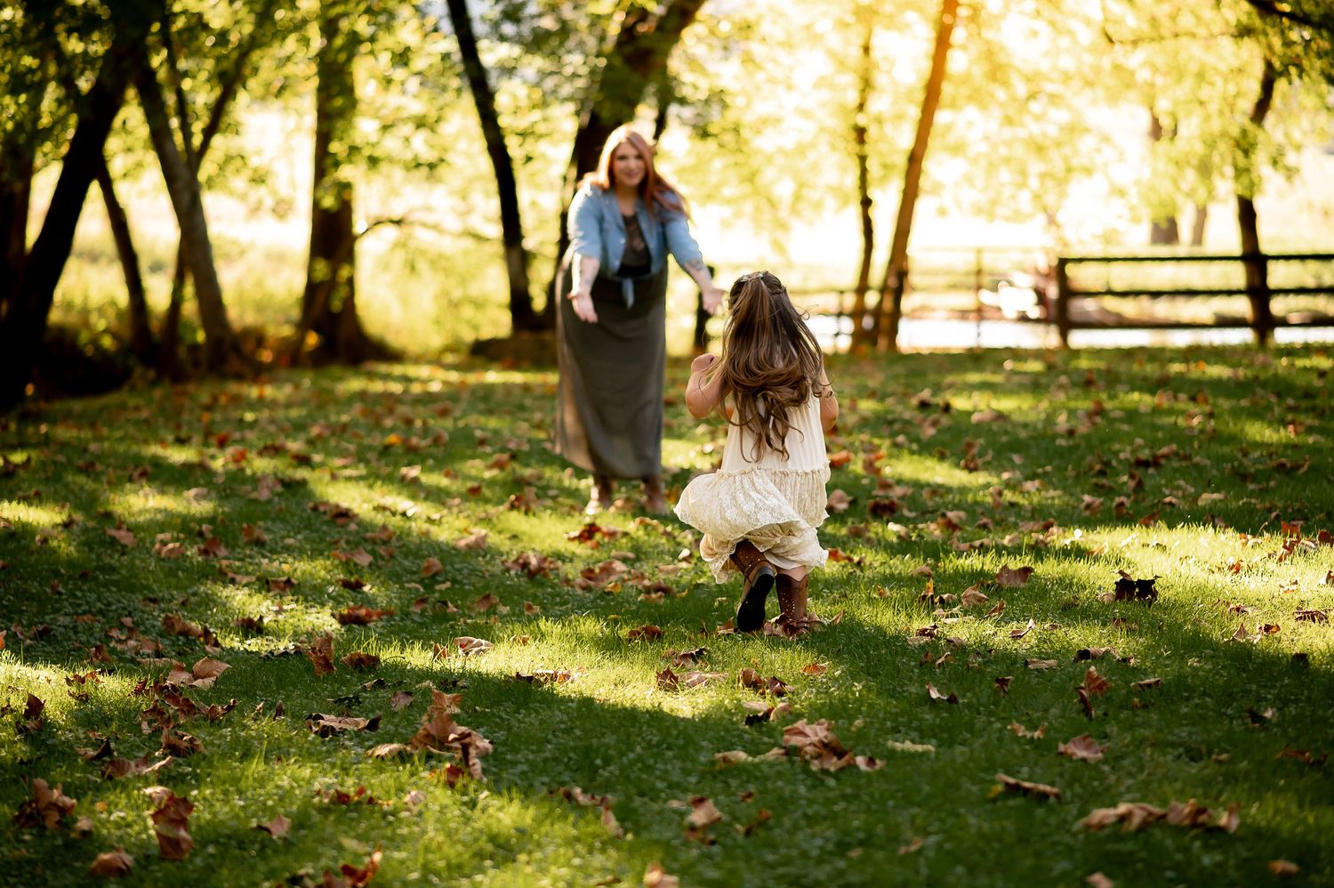 Autumn scene with people playing among fallen leaves in a sunlit park.