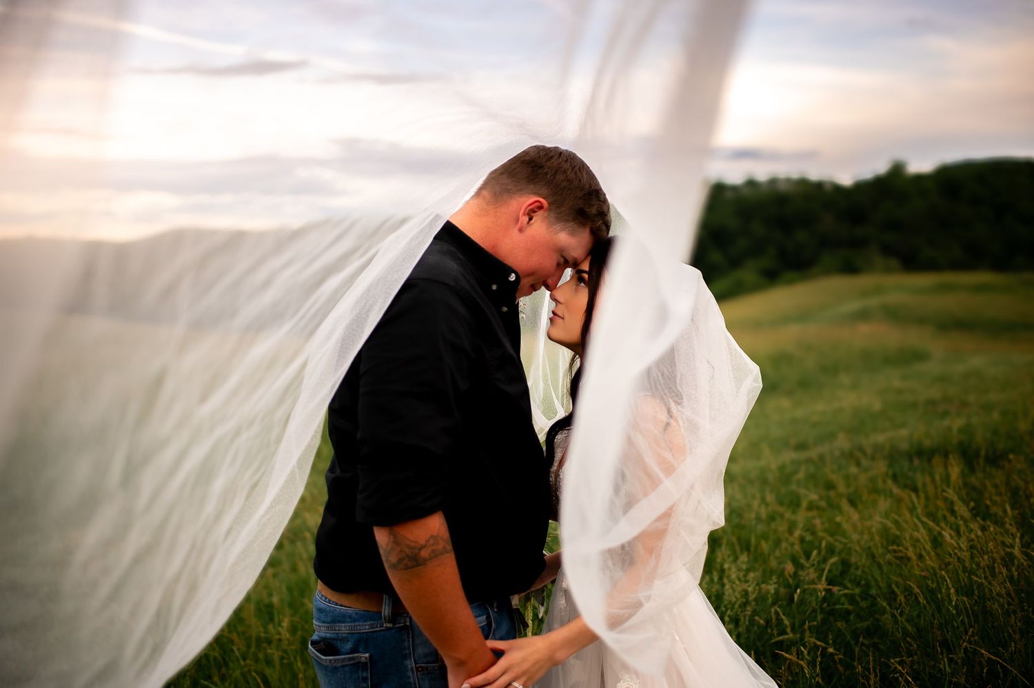 A creative wedding photo with flowing veil catching wind in golden evening light.