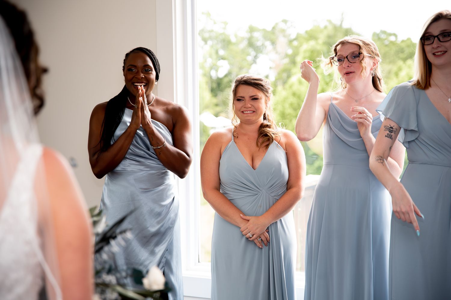 Bridesmaids in light blue dresses react emotionally during a wedding moment.
