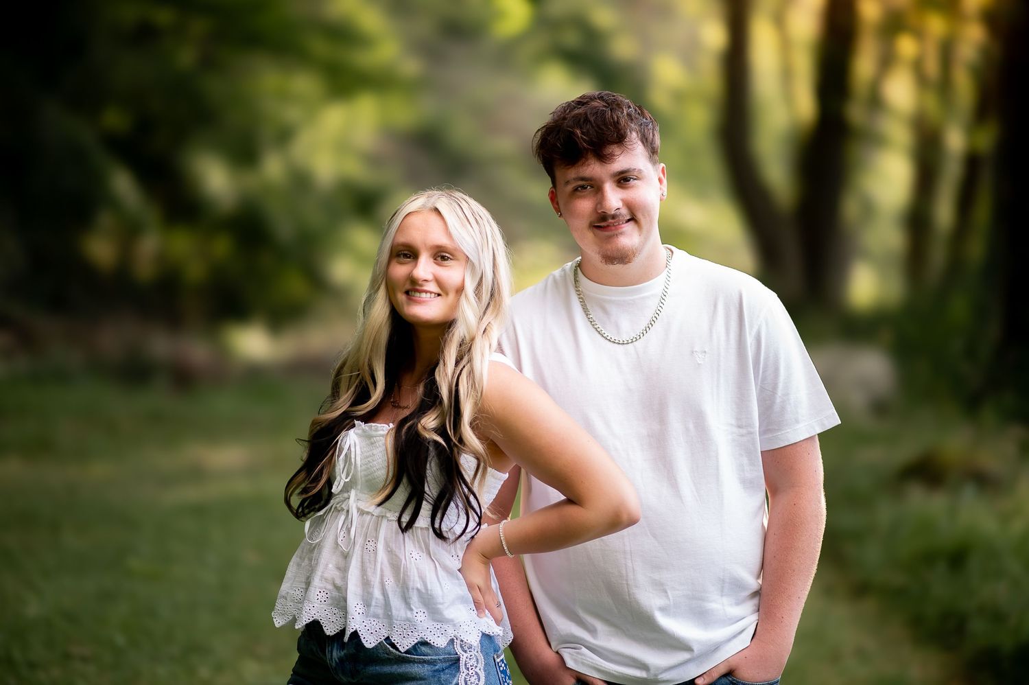 Casual outdoor couple portrait on wooded path in summer attire.