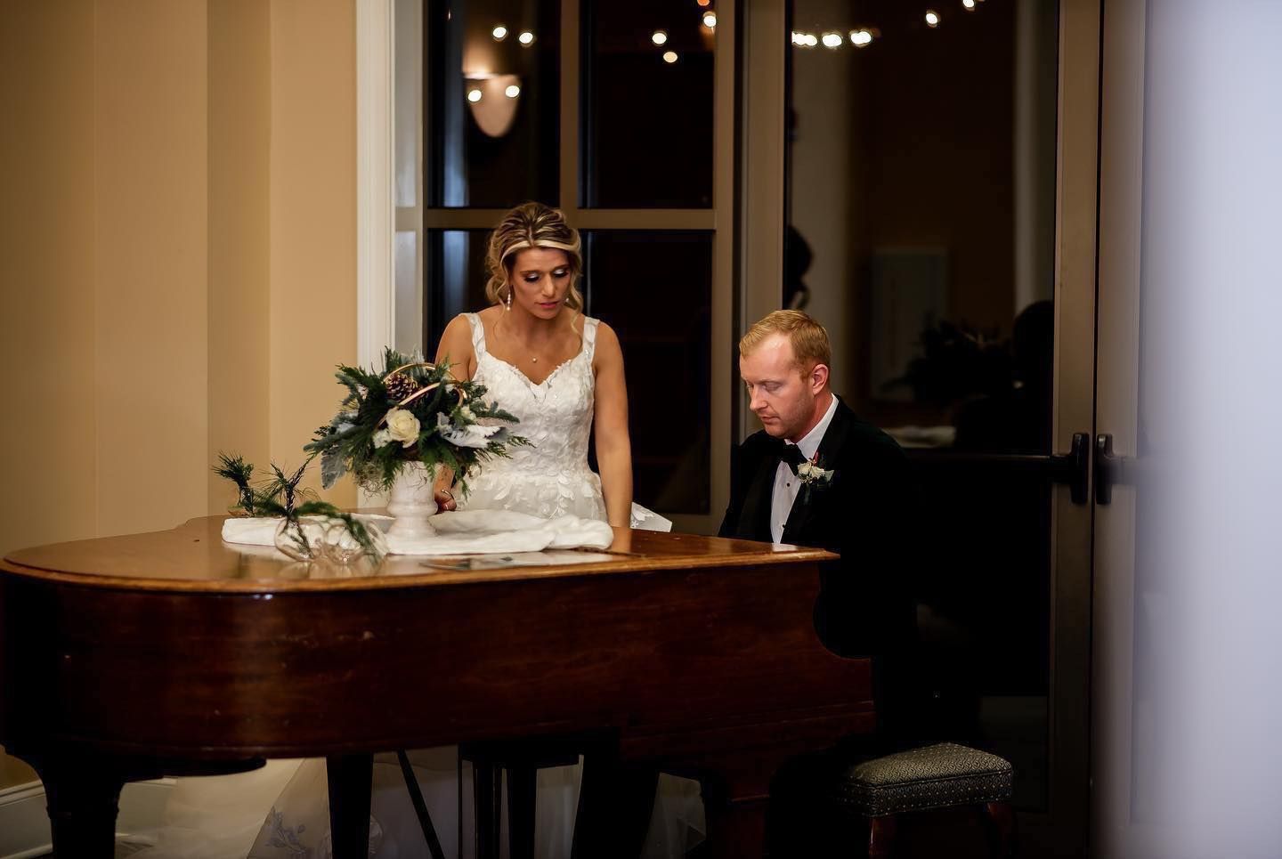 Wedding couple shares an intimate moment at a grand piano.