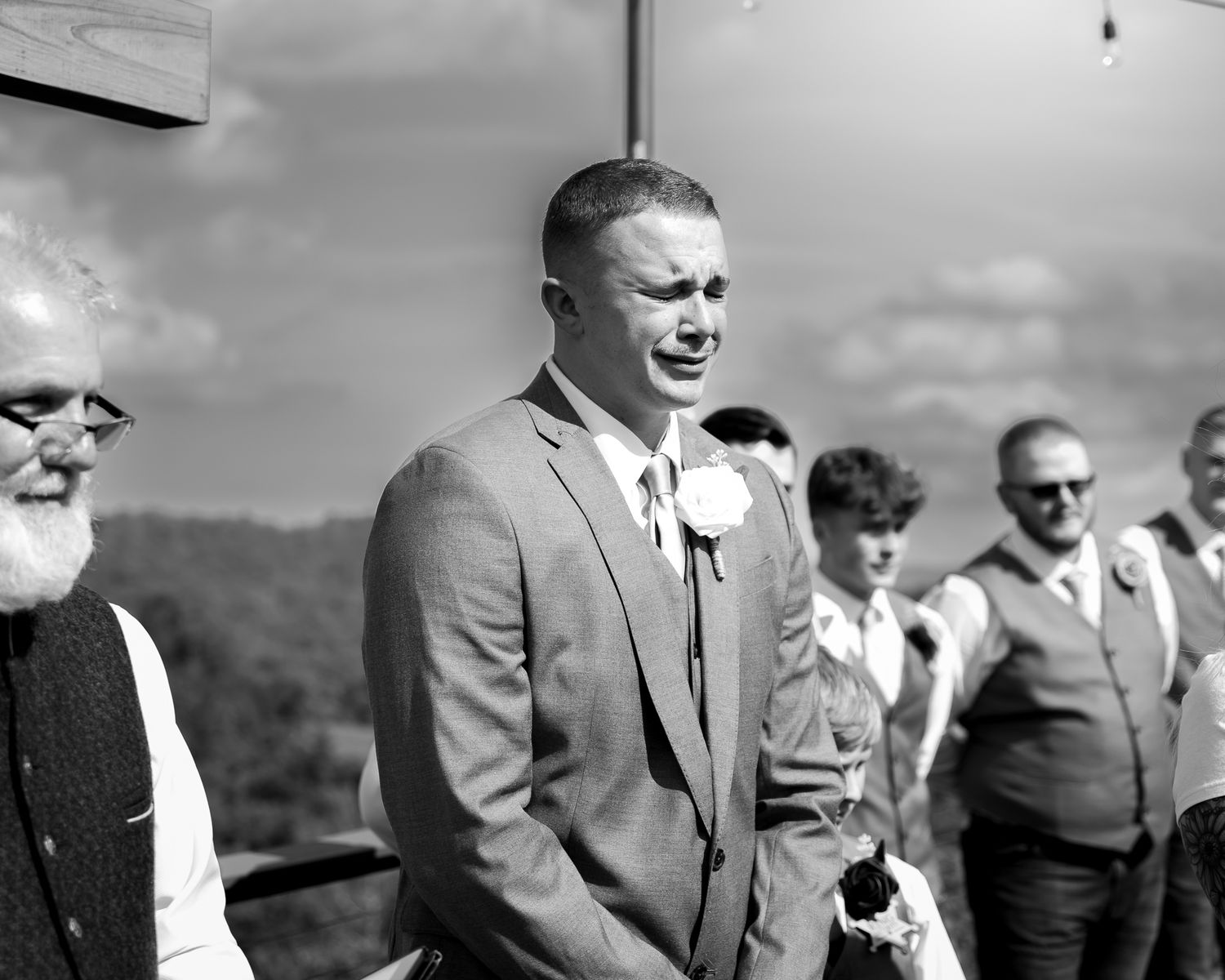 Wedding guests and party members laughing together during an outdoor ceremony.