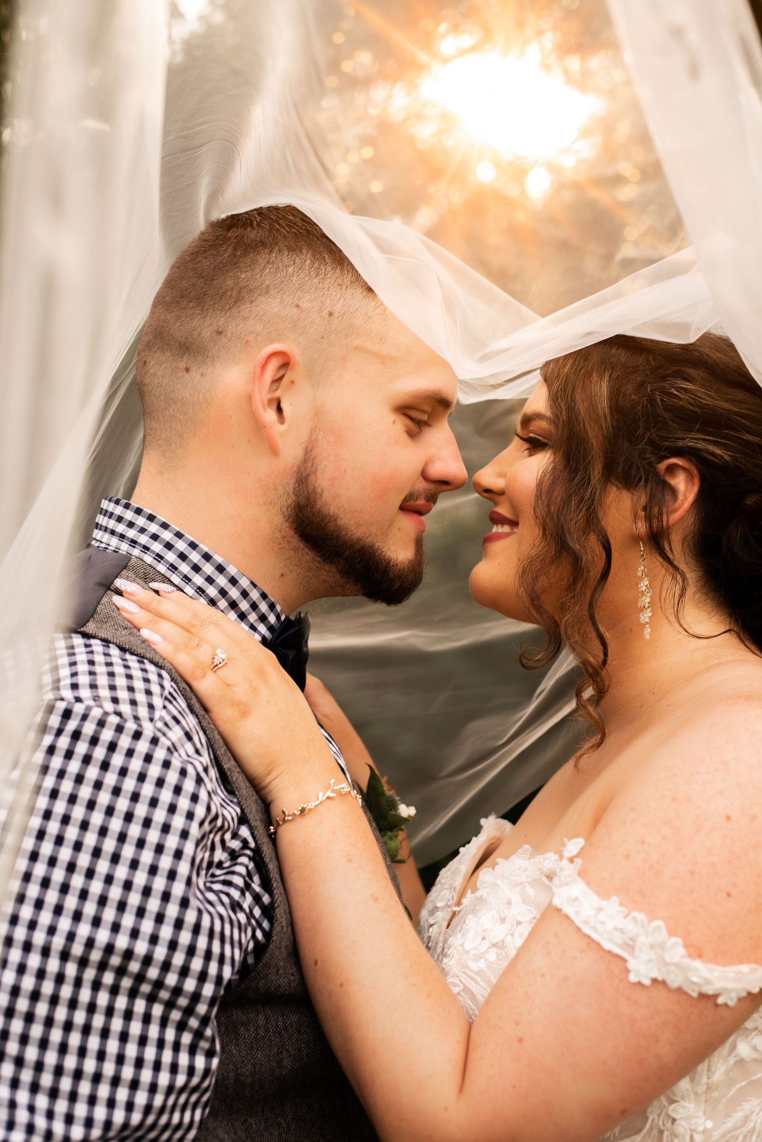 Intimate wedding portrait with soft golden lighting and romantic veil detail.