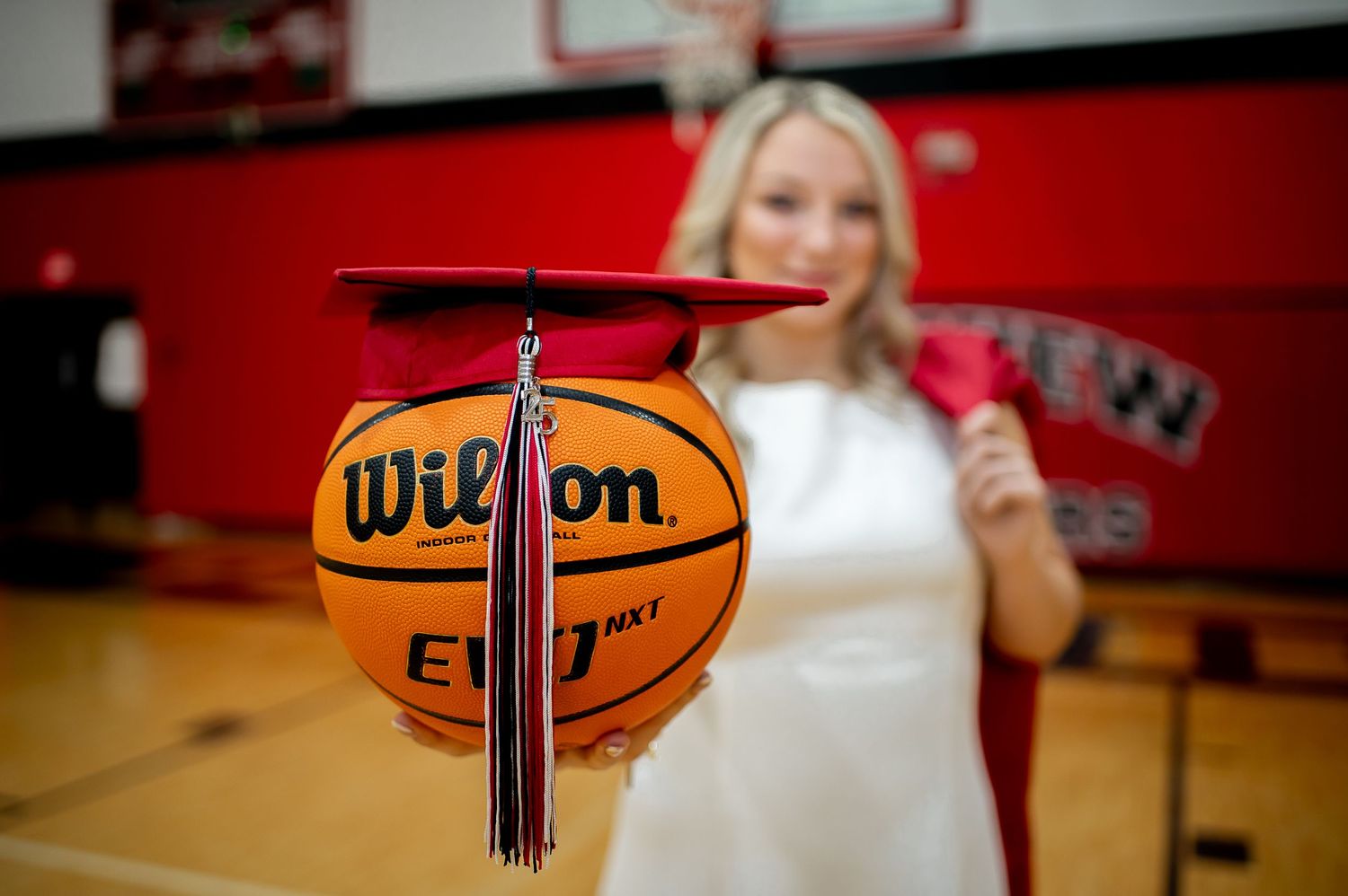 Multiple basketballs arranged with graduation caps in a gymnasium setting.