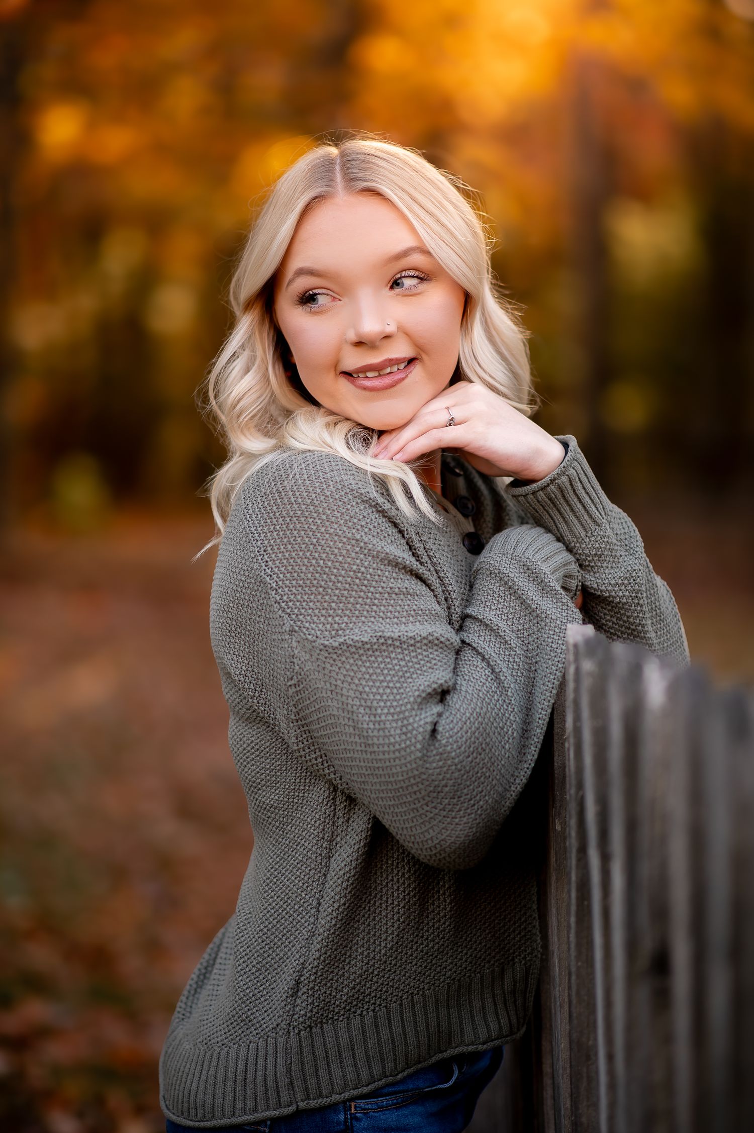 Autumn senior portrait with gray sweater against fall foliage.