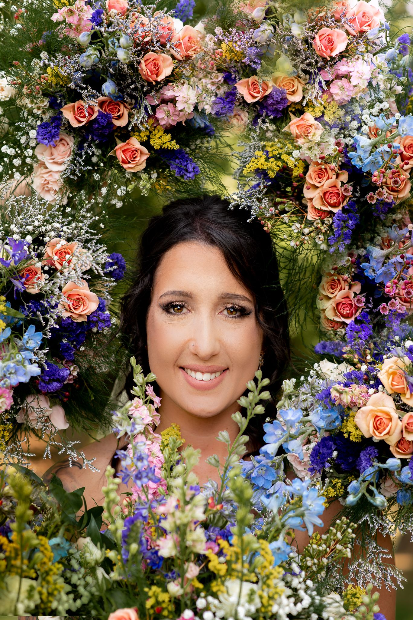 A floral crown made of pink roses, blue flowers, and greenery creates a stunning display.