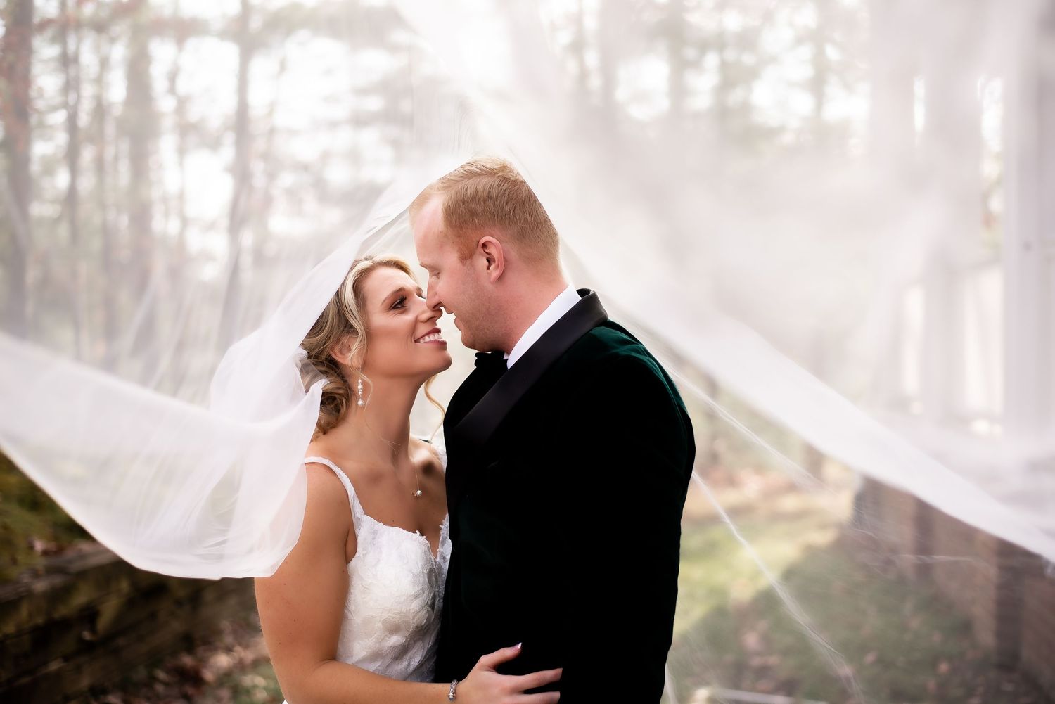 A romantic wedding portrait captured with dreamy sunlight filtering through trees.