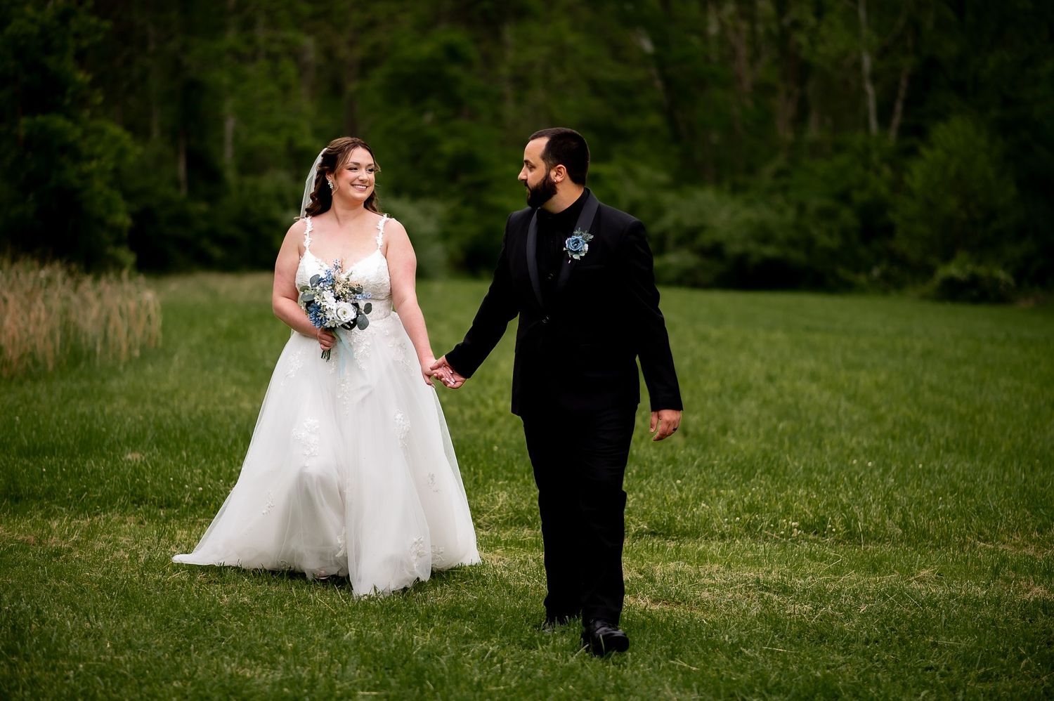 A couple strolls across a lush green lawn during their wedding.