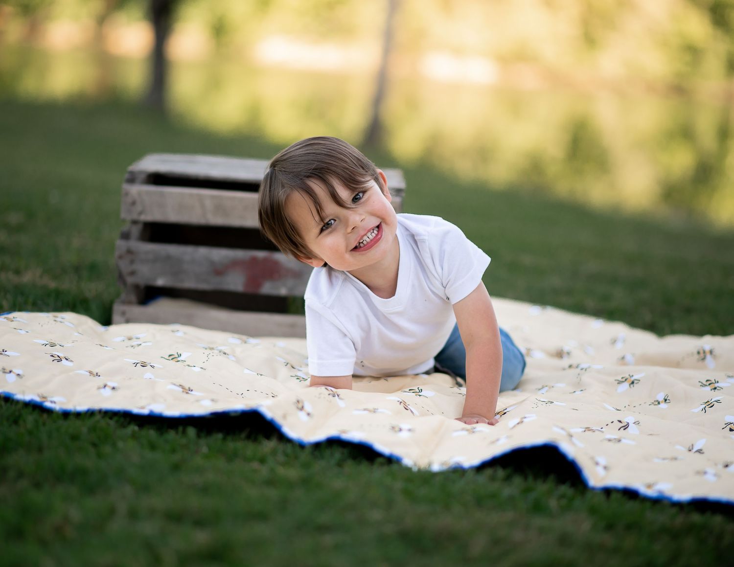 Child laying on a blanket in a sunny garden during an outdoor photo session.