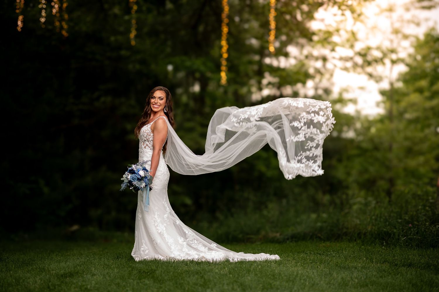Flowing lace veil catching the breeze in an ethereal bridal portrait at sunset.