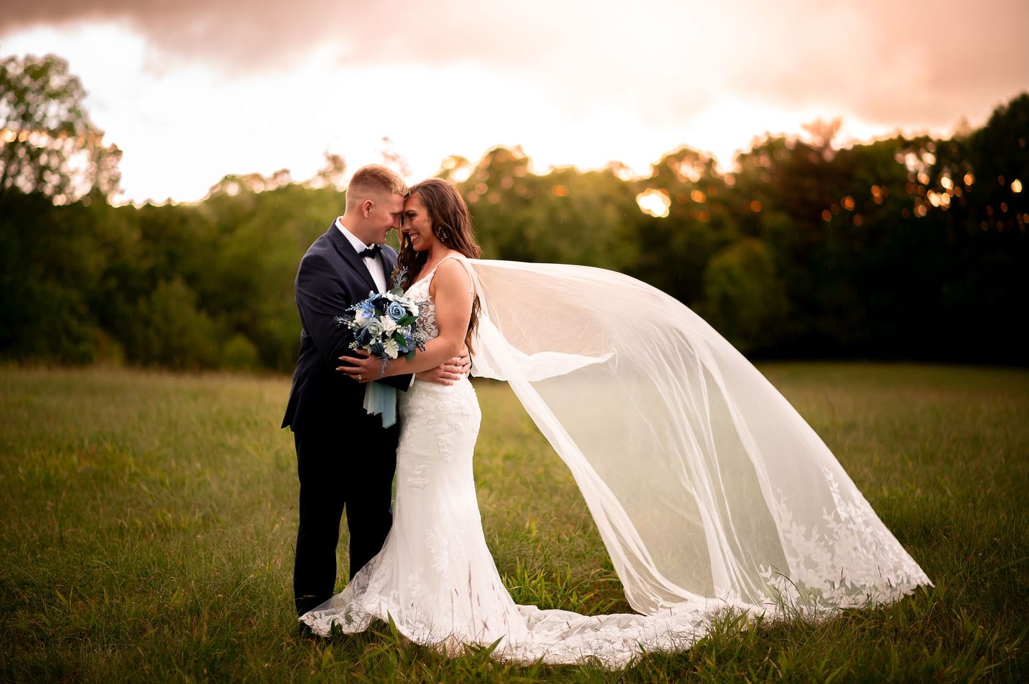 Romantic sunset portrait with flowing veil in an open field.