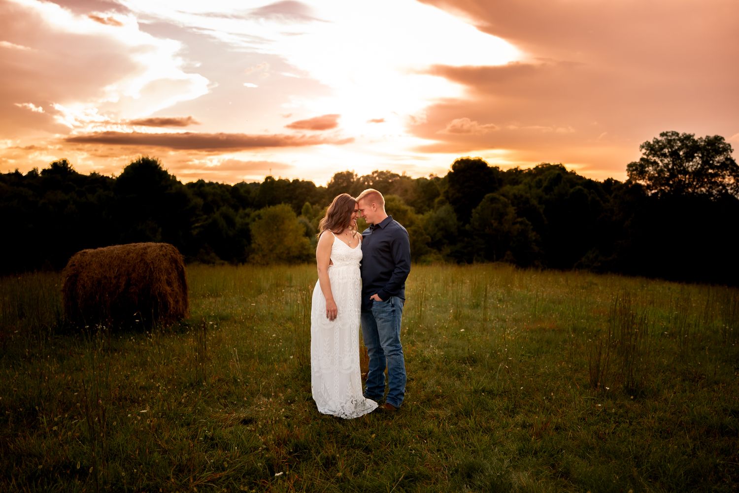 A romantic sunset moment captured in a golden field with dramatic orange sky overhead.